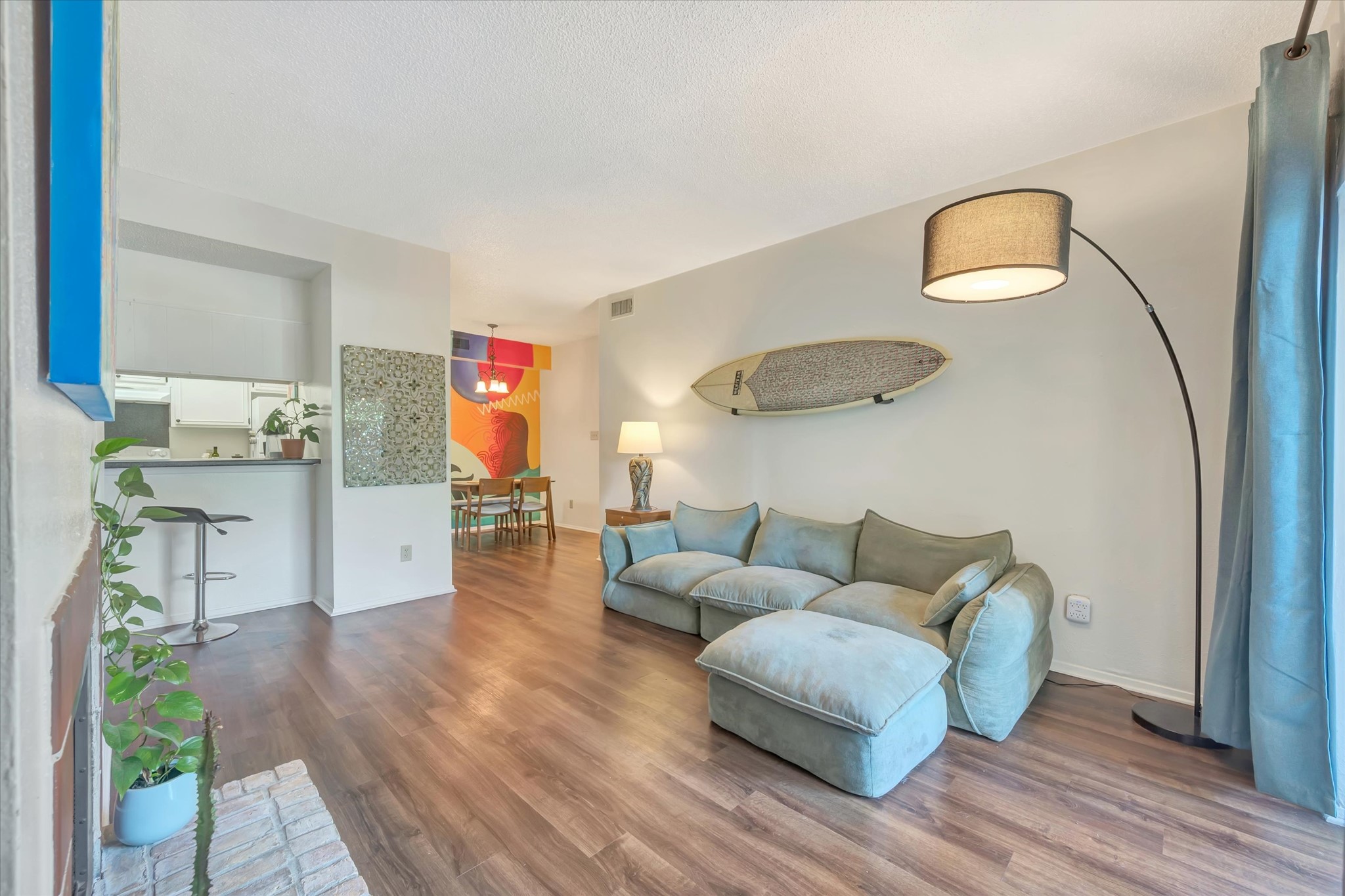 Living area with wood-look flooring and an open connection to the kitchen and dining space.