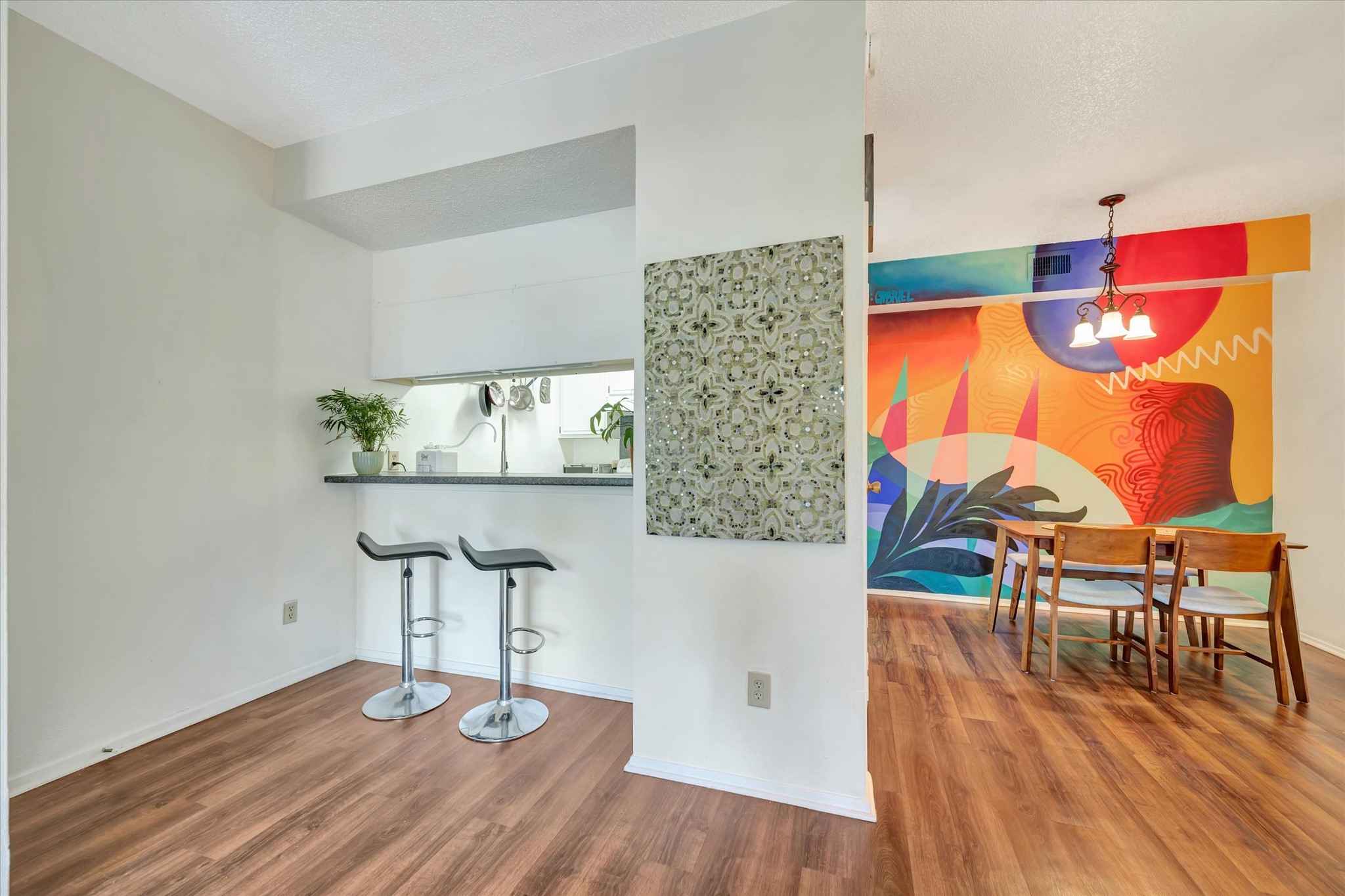 Kitchen and dining area featuring a breakfast bar, wood-look flooring and a colorful custom mural.