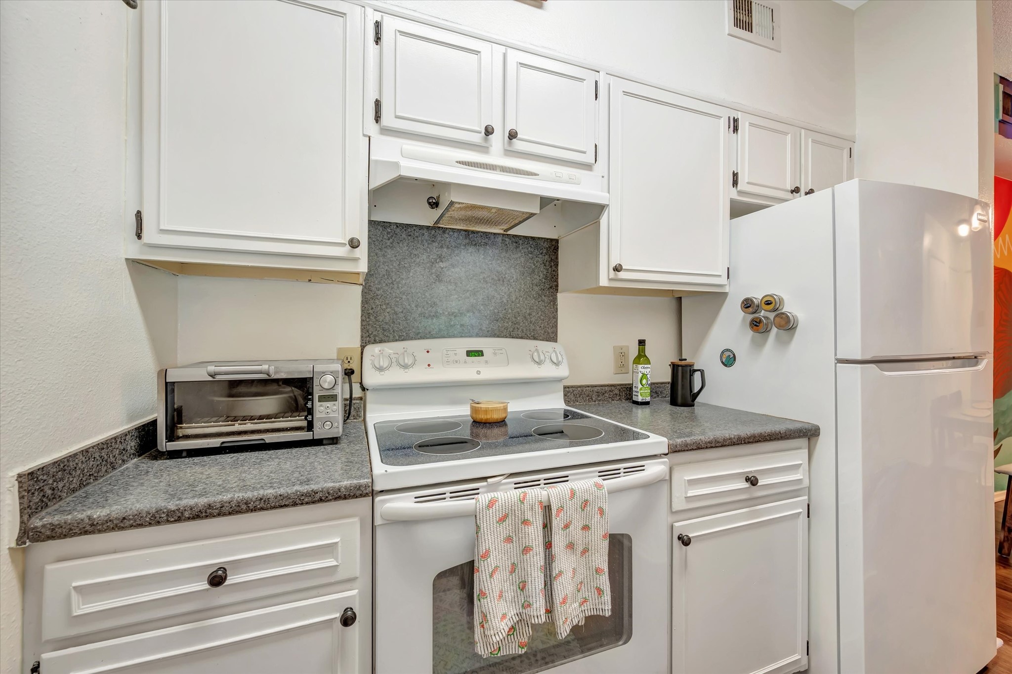 Additional kitchen view showing the refrigerator, range and upper and lower cabinetry.
