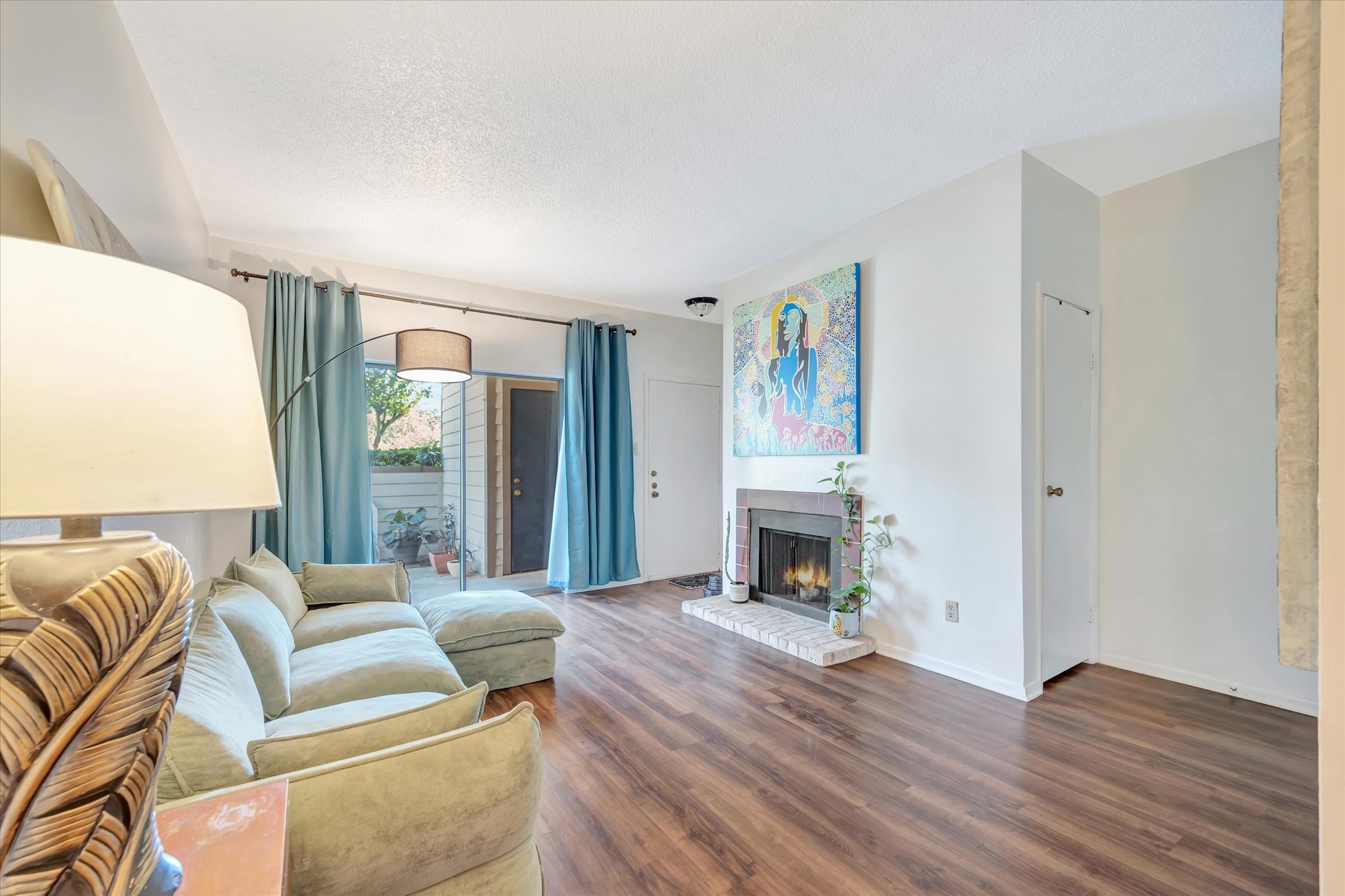 Another view of the living area showing the seating space, wood-look flooring and sliding glass doors.