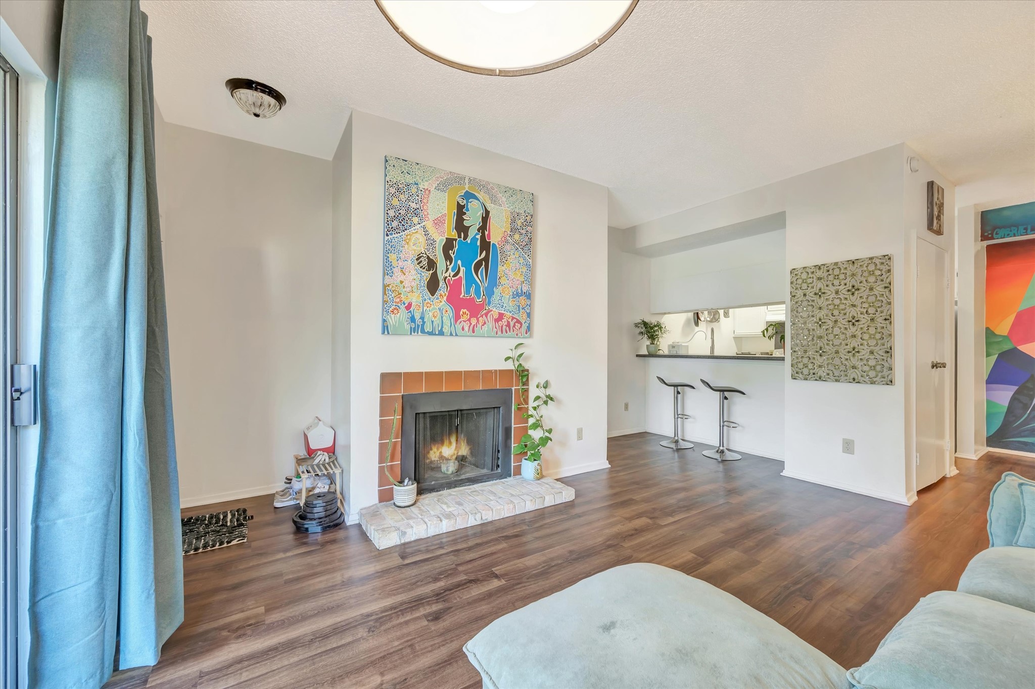 View across the living area toward the fireplace, breakfast bar and kitchen.
