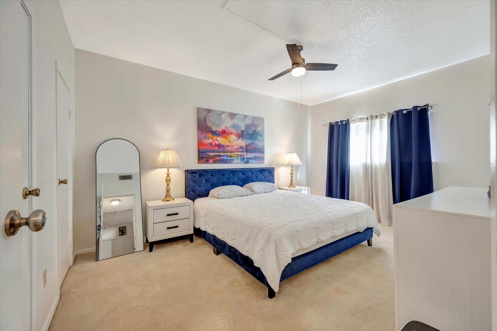 Primary bedroom with a ceiling fan, natural light and room for bedside furnishings.