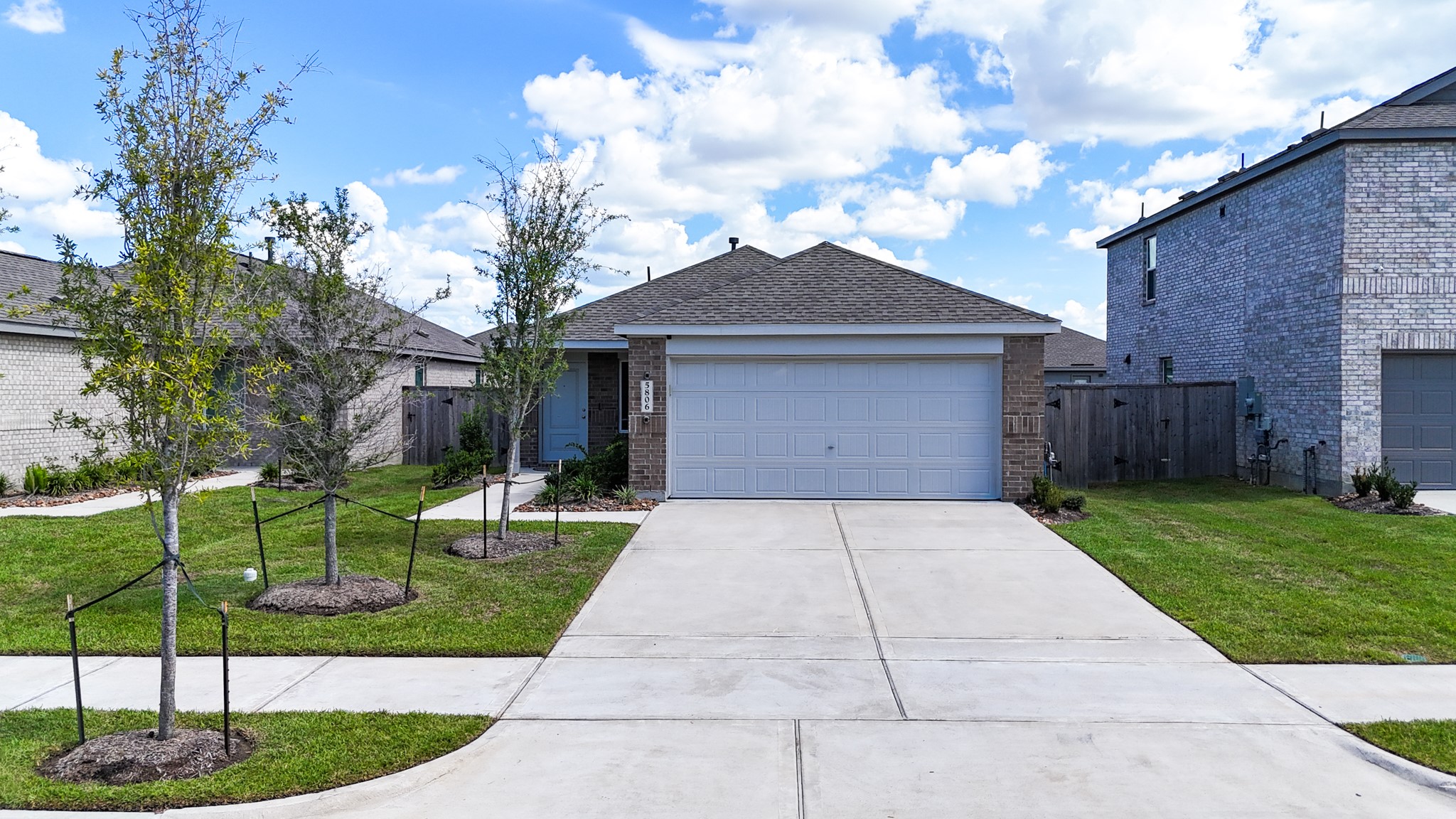 An immaculate two-car garage paired with an expansive concrete driveway offers plenty of parking for family and guests.