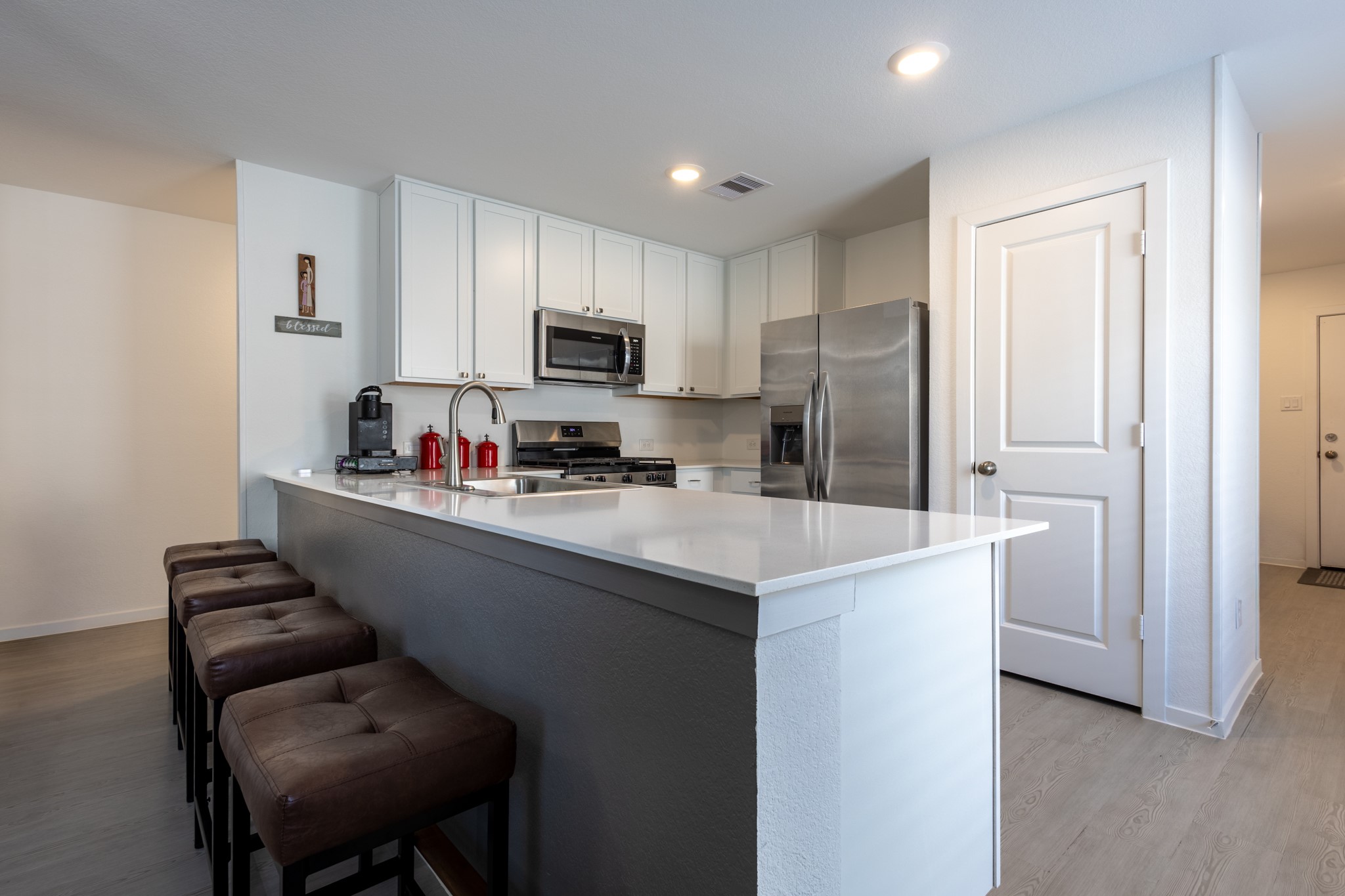 The central kitchen island highlights a fabulous custom foot bar upgrade along the base, making it the perfect spot for casual counter-height dining.