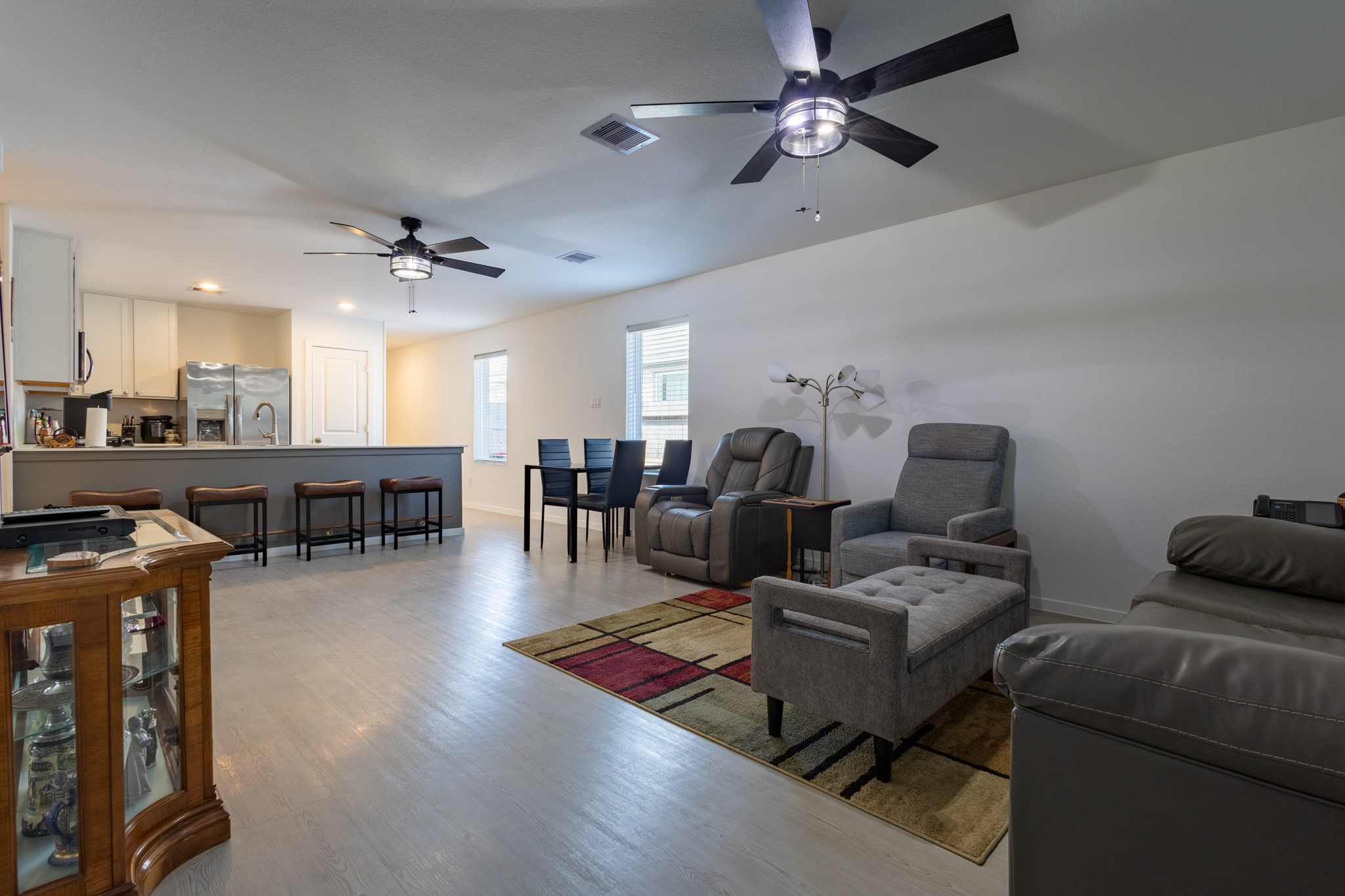 An expansive, light-filled family area showing off the move-in-ready upgrades, including a high-efficiency ceiling fan and custom window blinds.