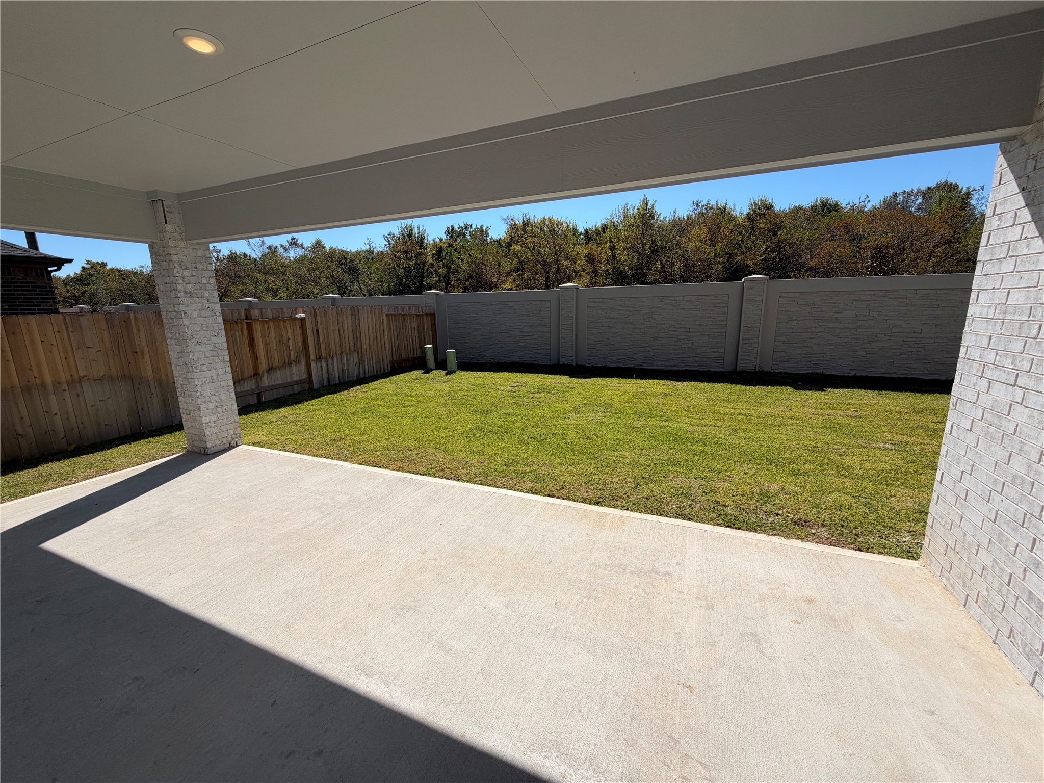 Spacious backyard with a covered patio, perfect for outdoor entertaining, surrounded by privacy fencing and lush greenery.