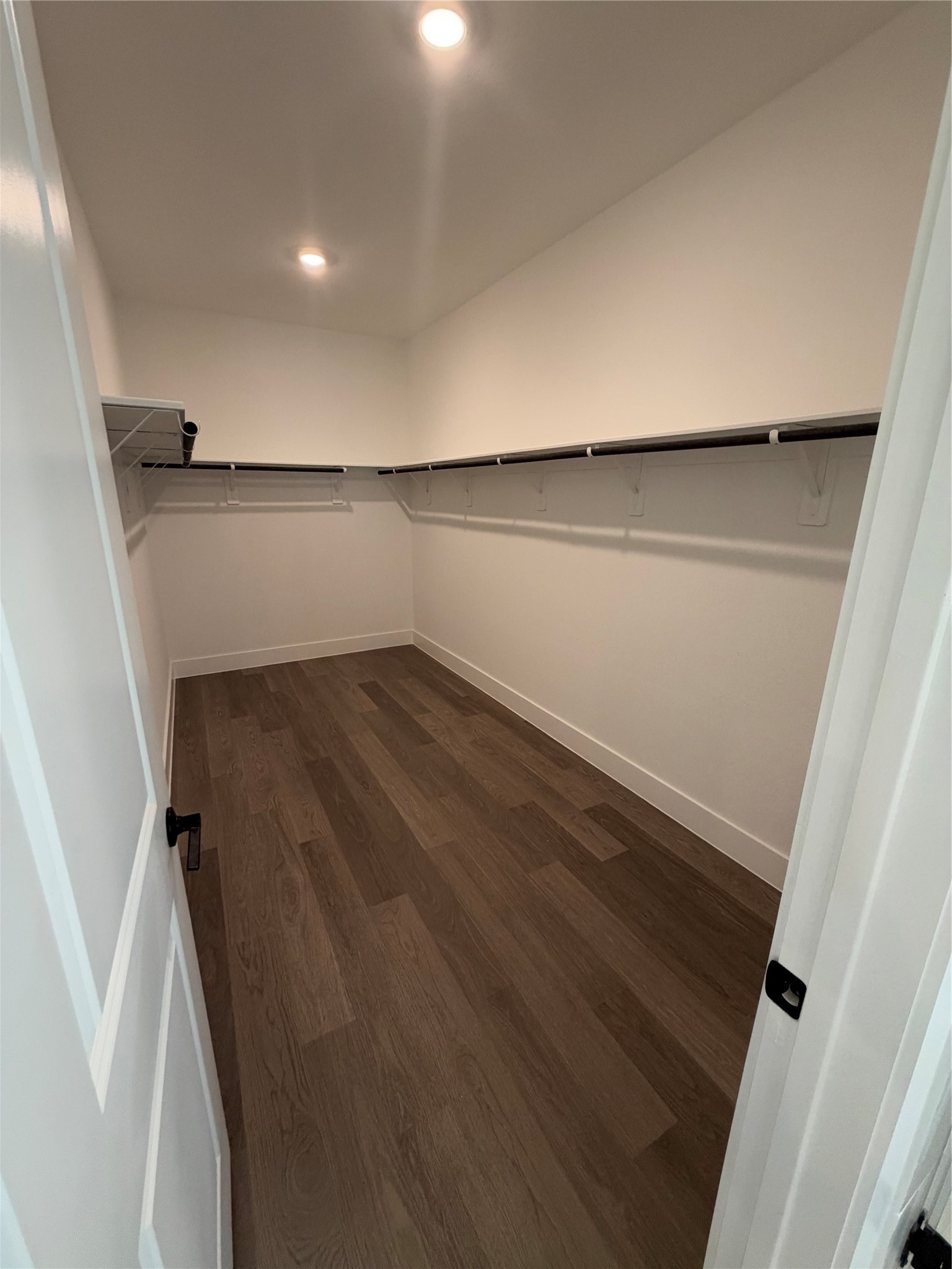 Spacious walk-in closet with sleek hardwood flooring and ample hanging space for all your storage needs.