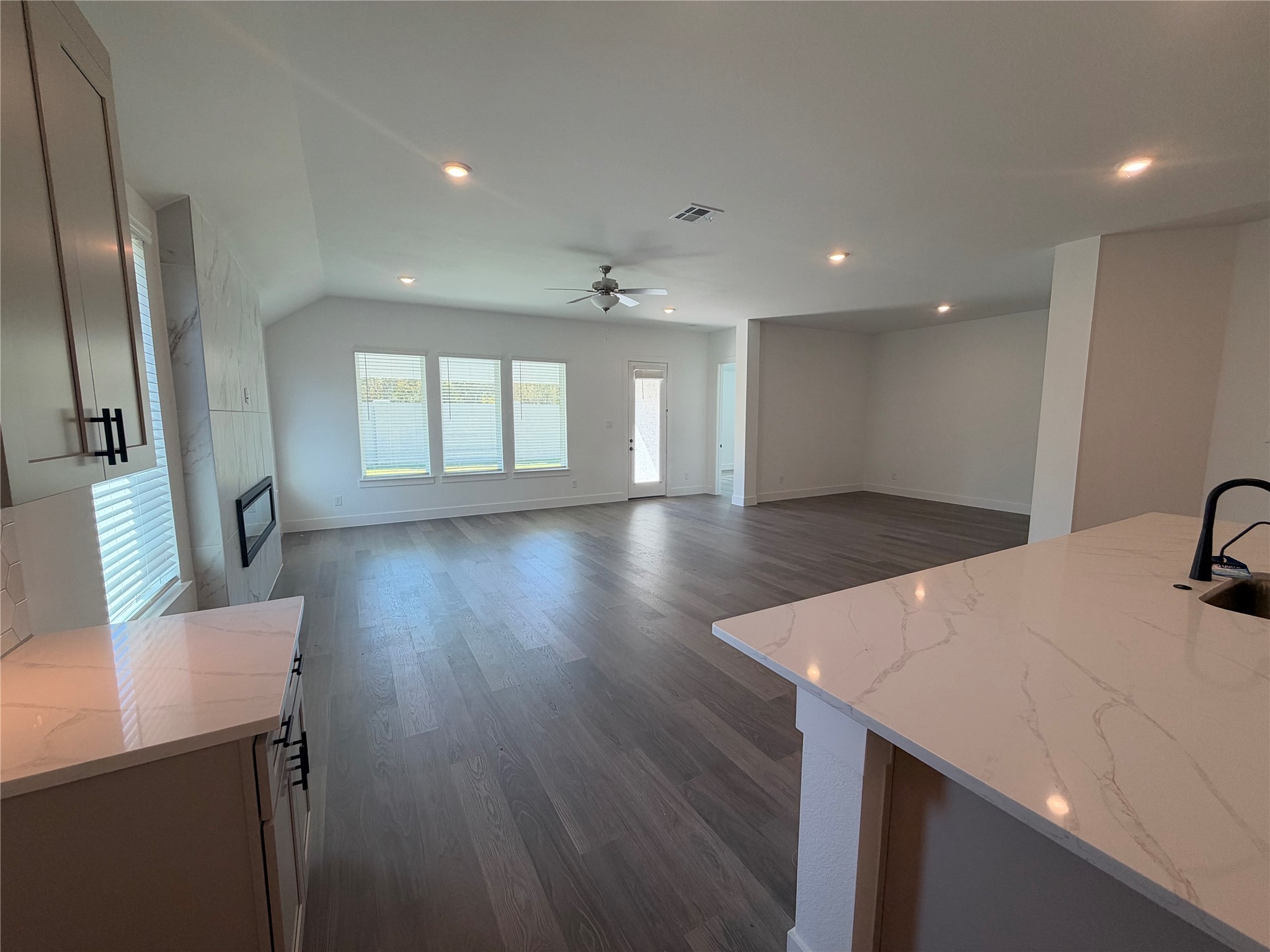 Spacious open-concept living/dining area with elegant hardwood floors and abundant natural light from large windows.