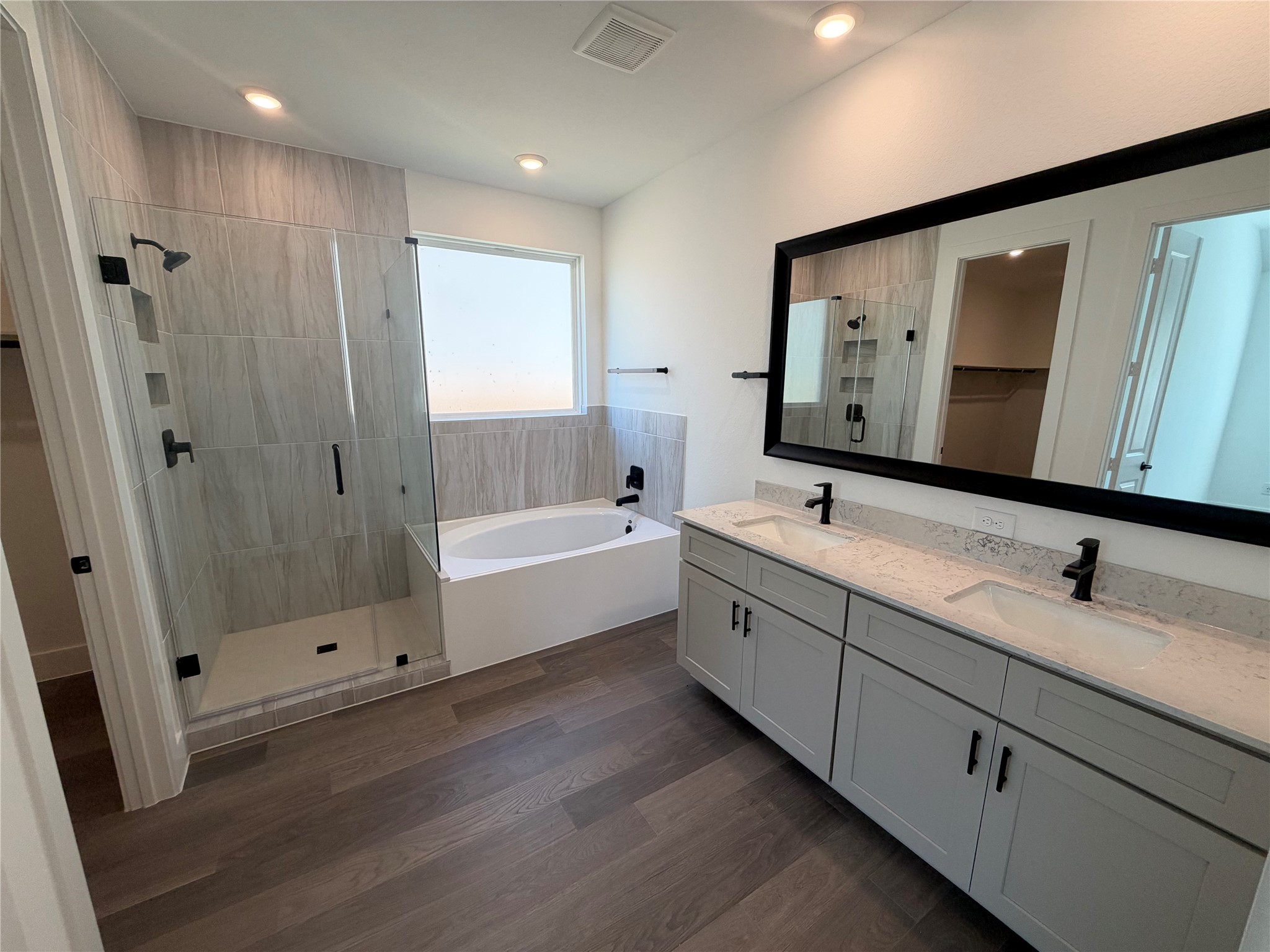 Elegant bathroom featuring a spacious glass-enclosed shower, a luxurious soaking tub, and a dual-sink vanity with sleek fixtures and ample storage.