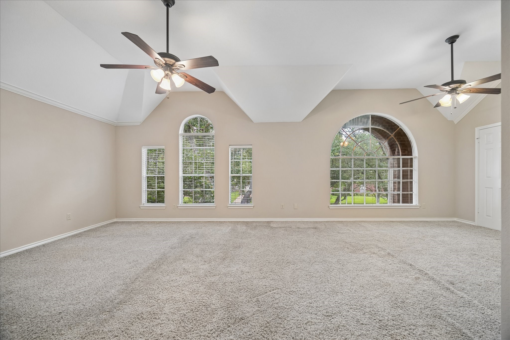 Another view of the primary bedroom with the windows looking out to the front of the house.  Soaring ceilings.