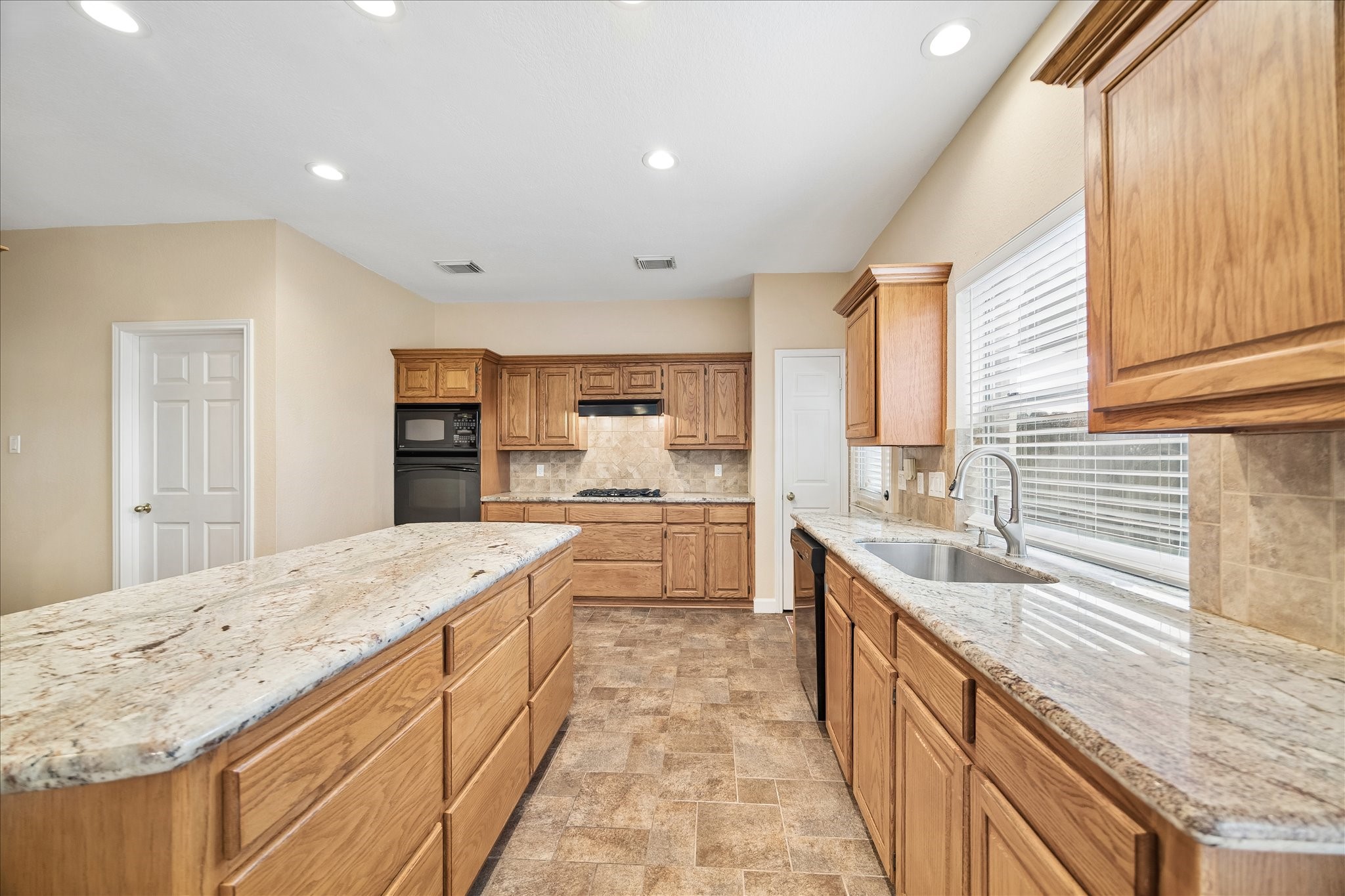 The granite is just stunning!  And backsplash.  This kitchen is made for entertaining family and guests.  Lots of storage.  The door by the back door is a closet (could be a second pantry).  The closed door on the left is the utility room.   Across from that (you cannot see it) is the large walk-in pantry.
