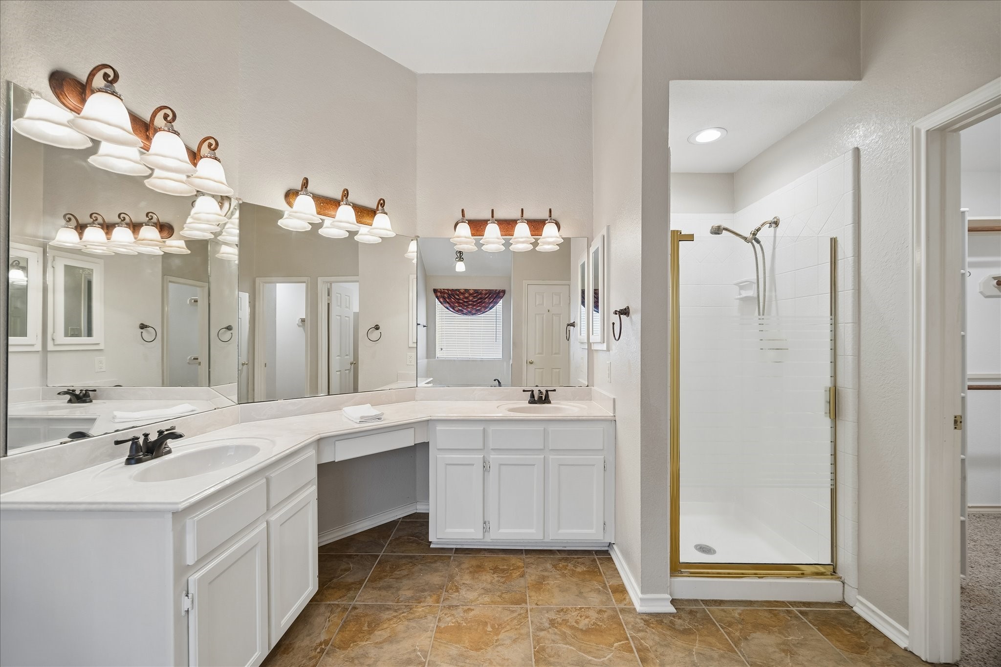 You enter the primary bathroom to the left of this picture.  Here you see the vanity and his and her sinks.  Separate shower, and jetted tub behind.  To the right of the shower is one of the 2 walk-in closets in the bathroom.