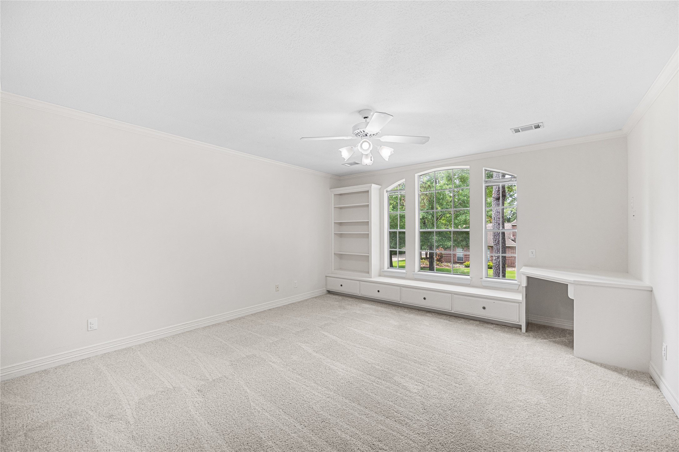 Secondary bedroom with built-in desk, shelving, and window seat.