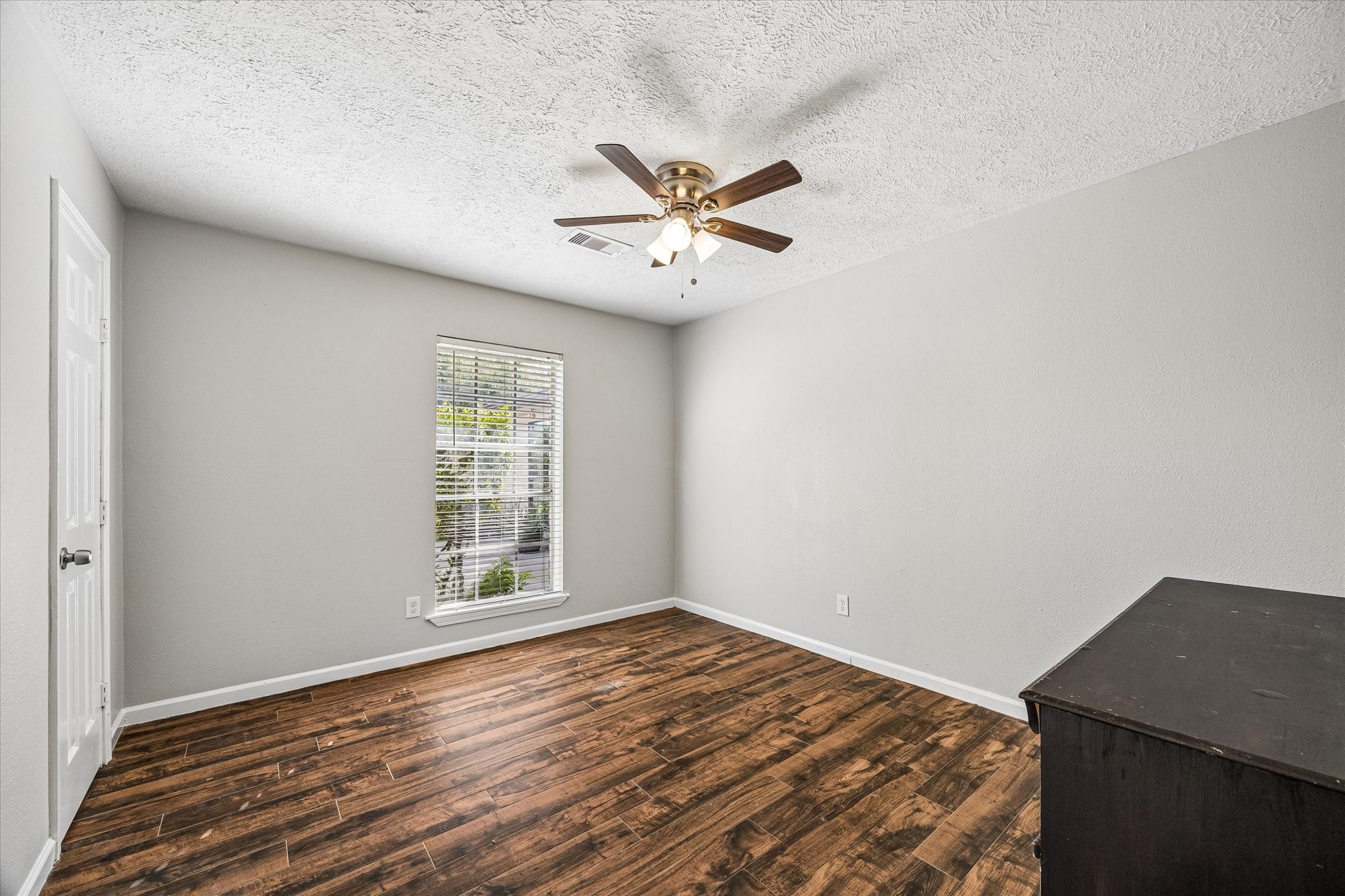 The secondary bedroom features wood-look tile flooring and a spacious walk-in closet, combining style, comfort, and practical storage.