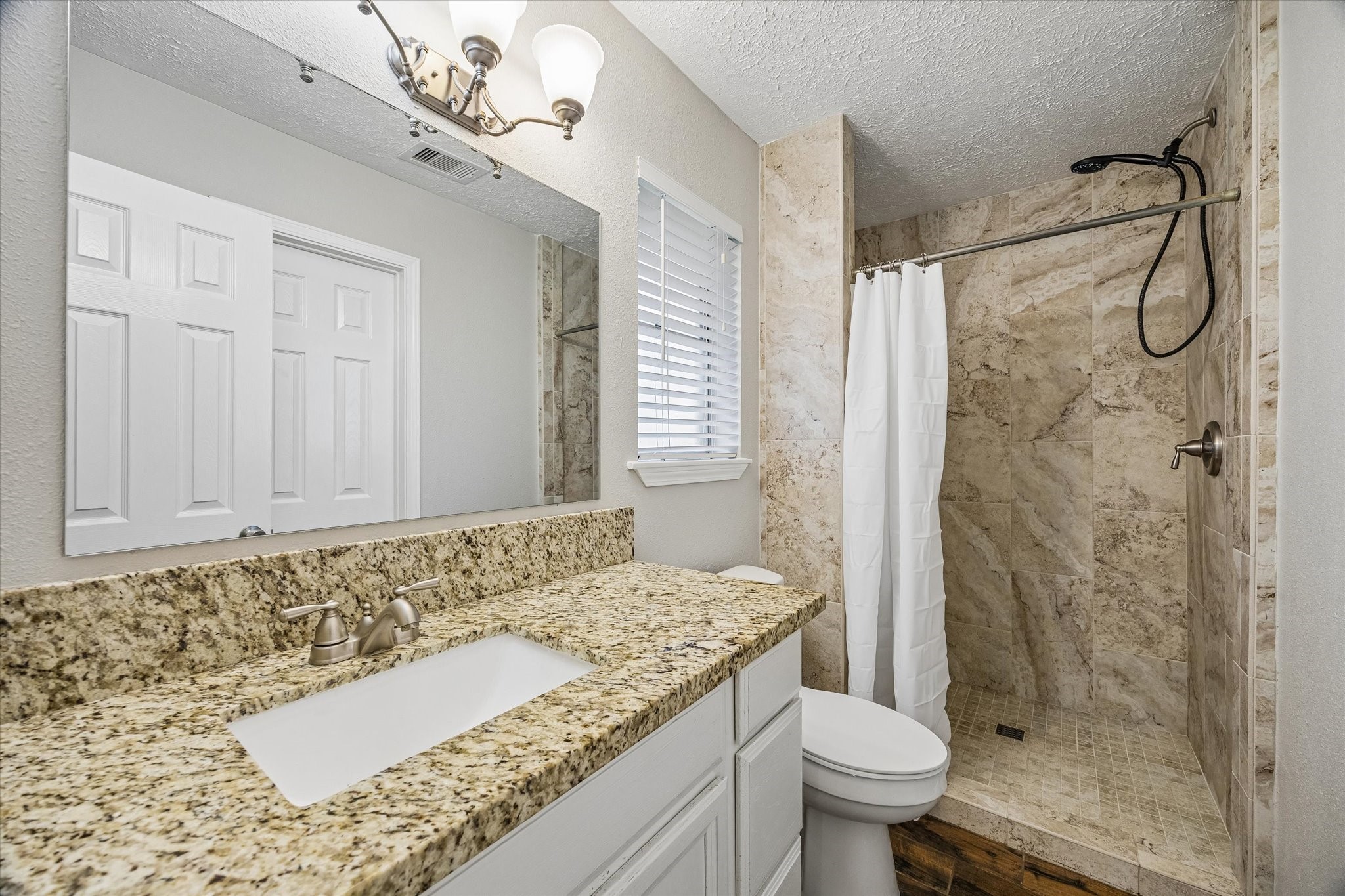 Elegant bathroom featuring a spacious granite countertop, modern fixtures, and a luxurious tiled walk-in shower.