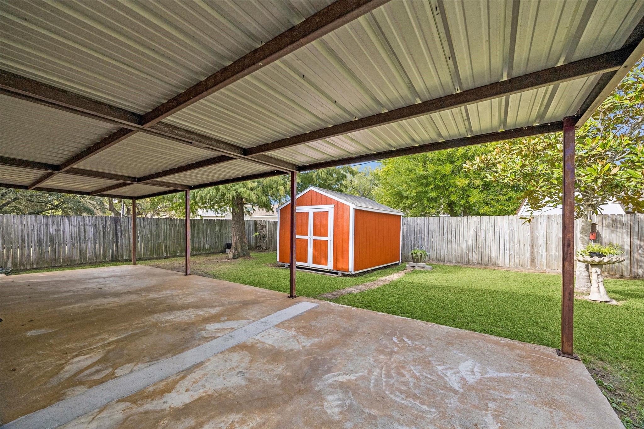 Spacious covered patio overlooking a well-maintained backyard with a  storage shed, perfect for outdoor activities and storage.
