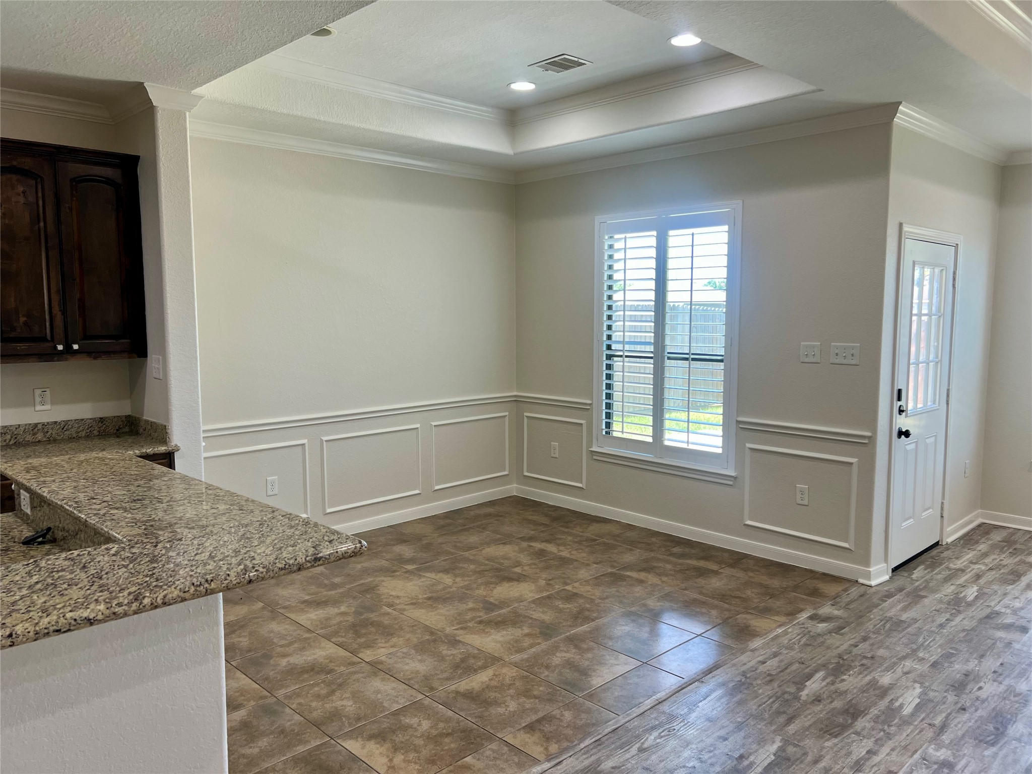 Dining area with chair rail, crown molding, tray ceiling and window overlooking backyard. Dining area with chair rail, crown molding, tray ceiling and window overlooking backyard.