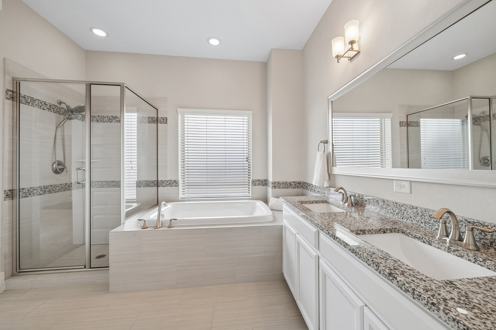 The spacious primary bathroom features granite countertops, dual sinks, and a separate tub and shower for added comfort and convenience.
