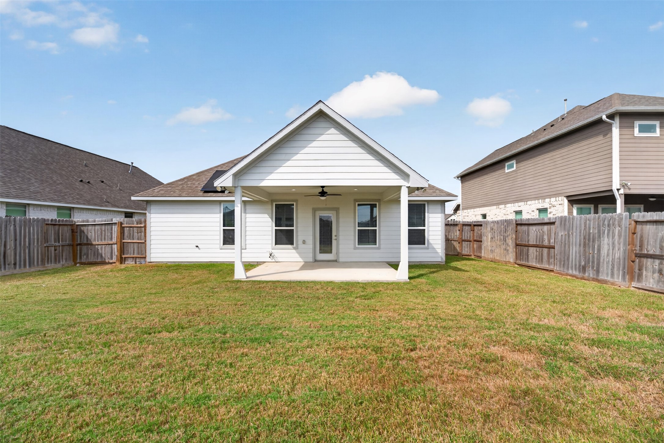 Charming backyard with a covered patio, perfect for outdoor gatherings, surrounded by a privacy fence.