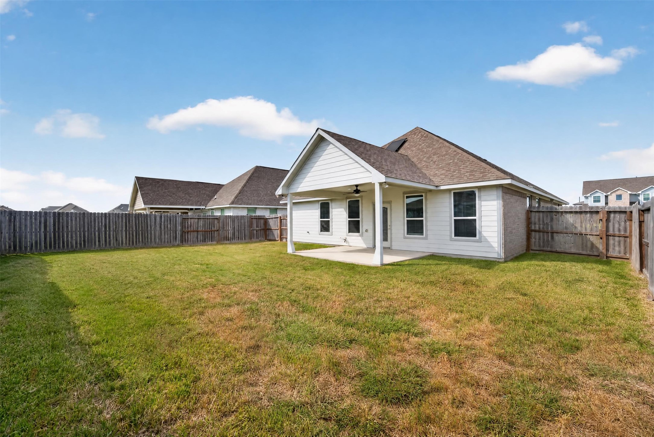 Charming backyard with a spacious lawn, perfect for outdoor activities, featuring a covered patio ideal for relaxing or entertaining.