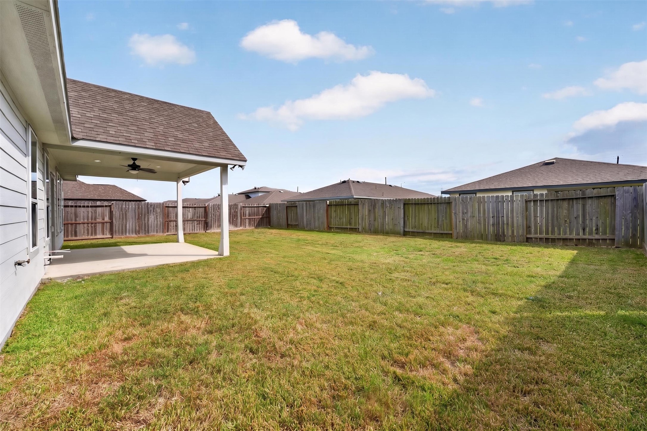 Spacious backyard with a covered patio, perfect for outdoor entertaining and relaxation, surrounded by a privacy fence.