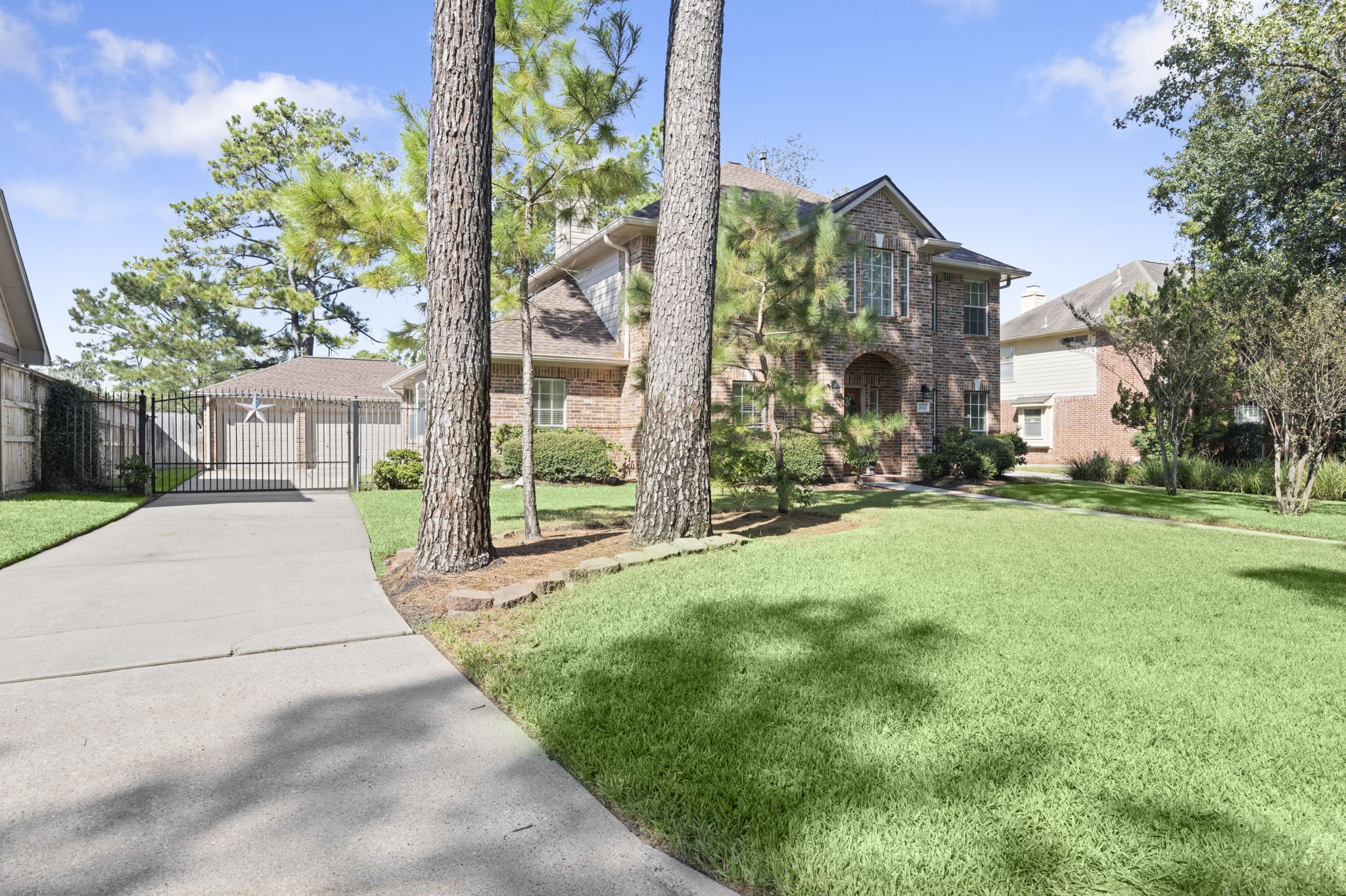 CURB APPEAL THAT MAKES A STATEMENT! Majestic mature pines frame the expansive front lawn, while an extra-long driveway with decorative wrought-iron gate leads to the detached 3-car garage. A covered walkway connects the garage to the home, adding everyday convenience to this beautifully established setting!