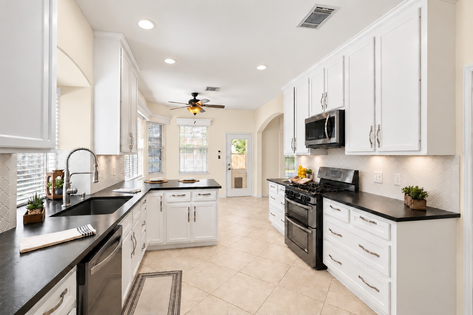 NOT YOUR ORDINARY KITCHEN! Thoughtfully reimagined with an extensive custom renovation, this gorgeous kitchen features handcrafted white cabinetry extending to the ceiling, stunning leathered quartz countertops with custom ogee-edge detailing, a beautiful gray arabesque tile backsplash, and sleek black stainless appliances. A deep undermount sink with professional-style pull-down faucet, recessed lighting, and abundant custom storage make this kitchen as functional as it is beautiful!
