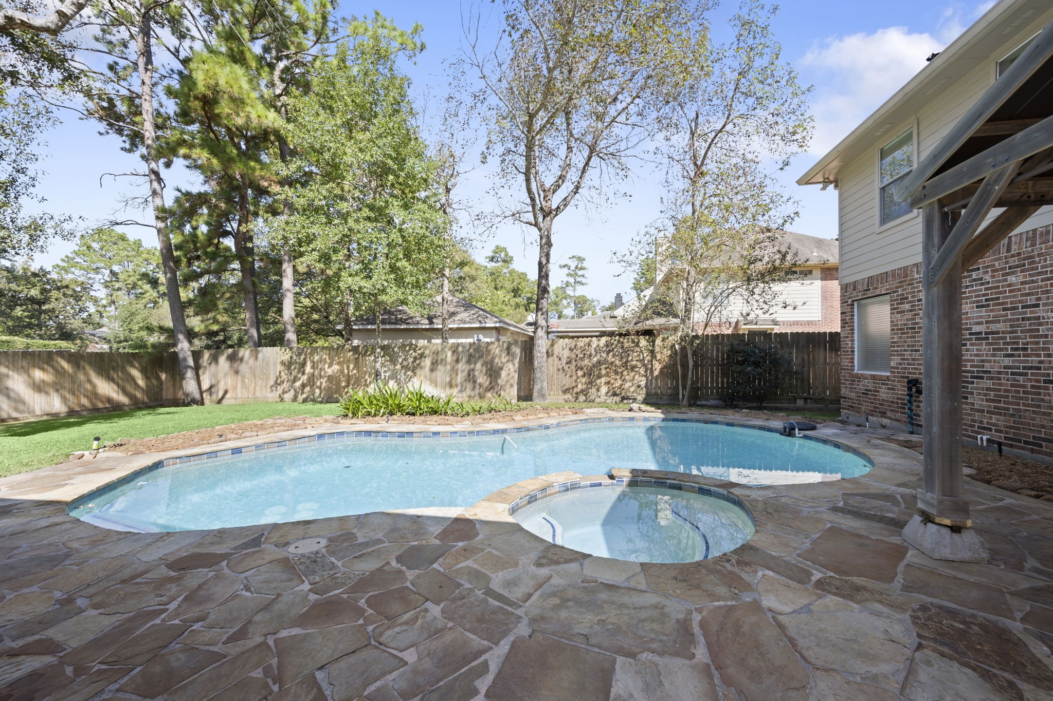 JUST IMAGINE THE MEMORIES YOU'LL MAKE! Sunny afternoons in the sparkling freeform pool, relaxing in the adjoining spa, and unforgettable gatherings with family and friends! Beautiful flagstone decking, mature shade trees, lush landscaping, and a wood privacy fence with a reinforced 24-inch base add to this inviting backyard retreat. Why vacation when you can STAYCATION?