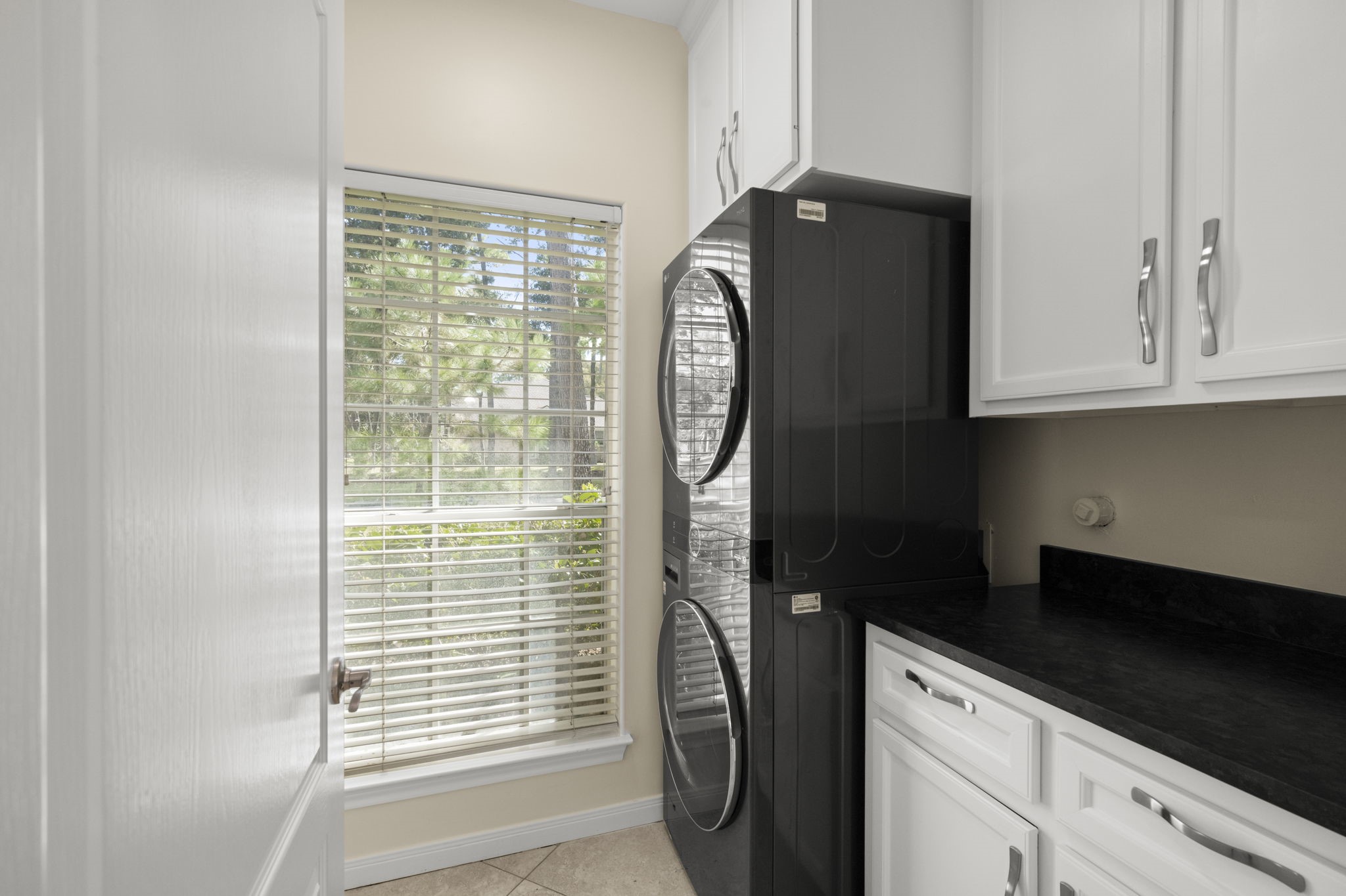 NOW THIS IS A LAUNDRY ROOM THAT WORKS OVERTIME! This generously sized 11 x 6 IN-HOUSE UTILITY ROOM offers SO MUCH MORE than a place to wash clothes! Enjoy a full-size stacked washer & dryer, spacious folding counter, CUSTOM BUILT-IN CABINETRY, drawers & FLOOR-TO-CEILING STORAGE tucked behind the door! Plenty of room for cleaning supplies, household essentials, vacuum cleaners & even those bulky kitchen appliancesslow cookers, blenders & more!