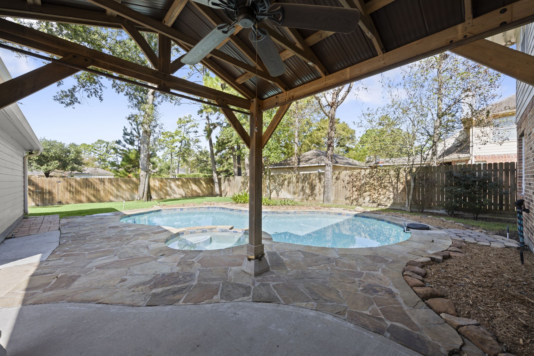 OUTDOOR ENTERTAINING AT ITS FINEST! This charming timber-framed gazebo features a ceiling fan, electricity, and a shaded retreat for dining alfresco or enjoying evenings under the stars! Just steps from the kitchen, entertaining is effortless. Gorgeous flagstone decking surrounds the sparkling freeform pool with its inviting curved edges and adjoining spa. From morning coffee to sunset cocktails and poolside gatherings, this backyard was made for making memories!