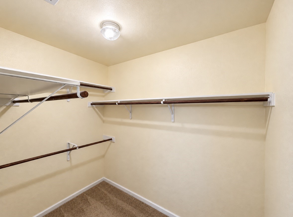 Room for your wardrobe & more! Generous walk-in closet with multiple hanging rods & shelving.