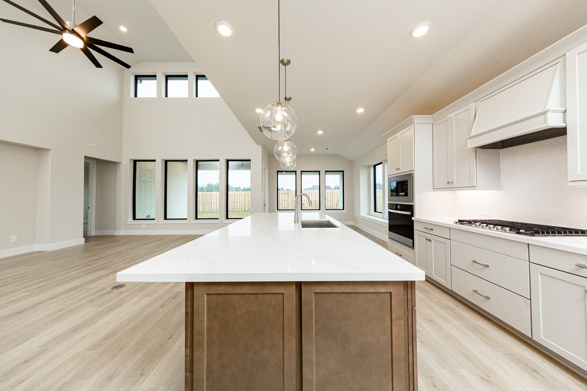 Three stunning clear glass orb pendant lights create an instant focal point above the kitchen island, offering both essential task lighting and a touch of modern sophistication.