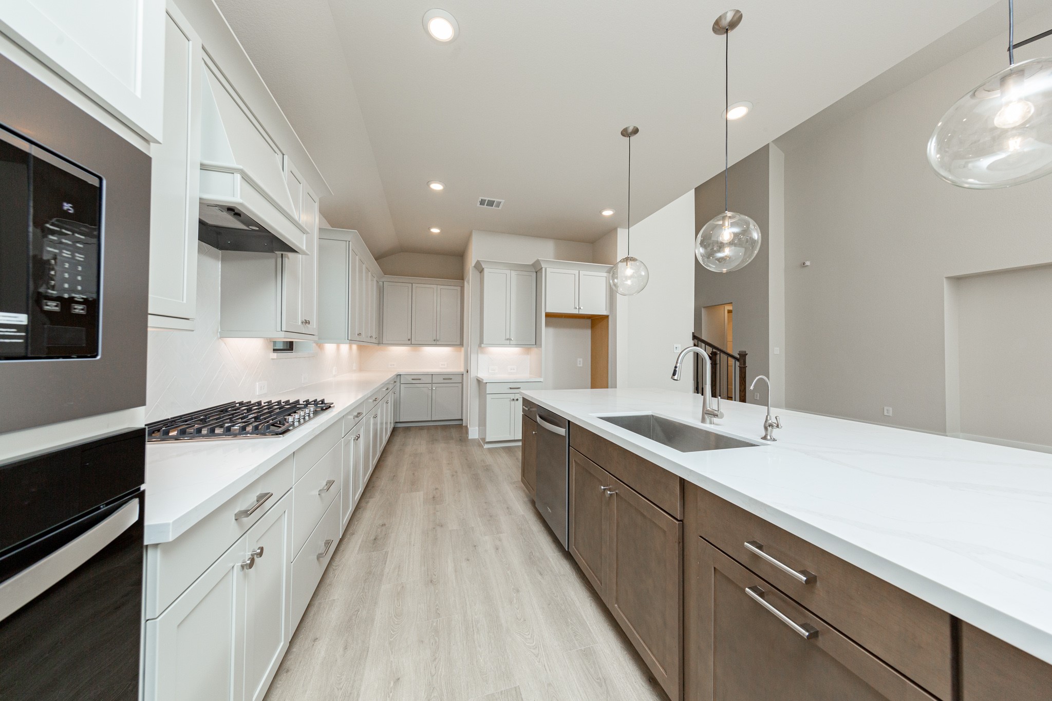 The kitchen includes Whirlpool stainless steel appliances: 30" gas cooktop, coordinating built-in stainless steel microwave, oven wall unit, and dishwasher suggesting a professional and polished space.