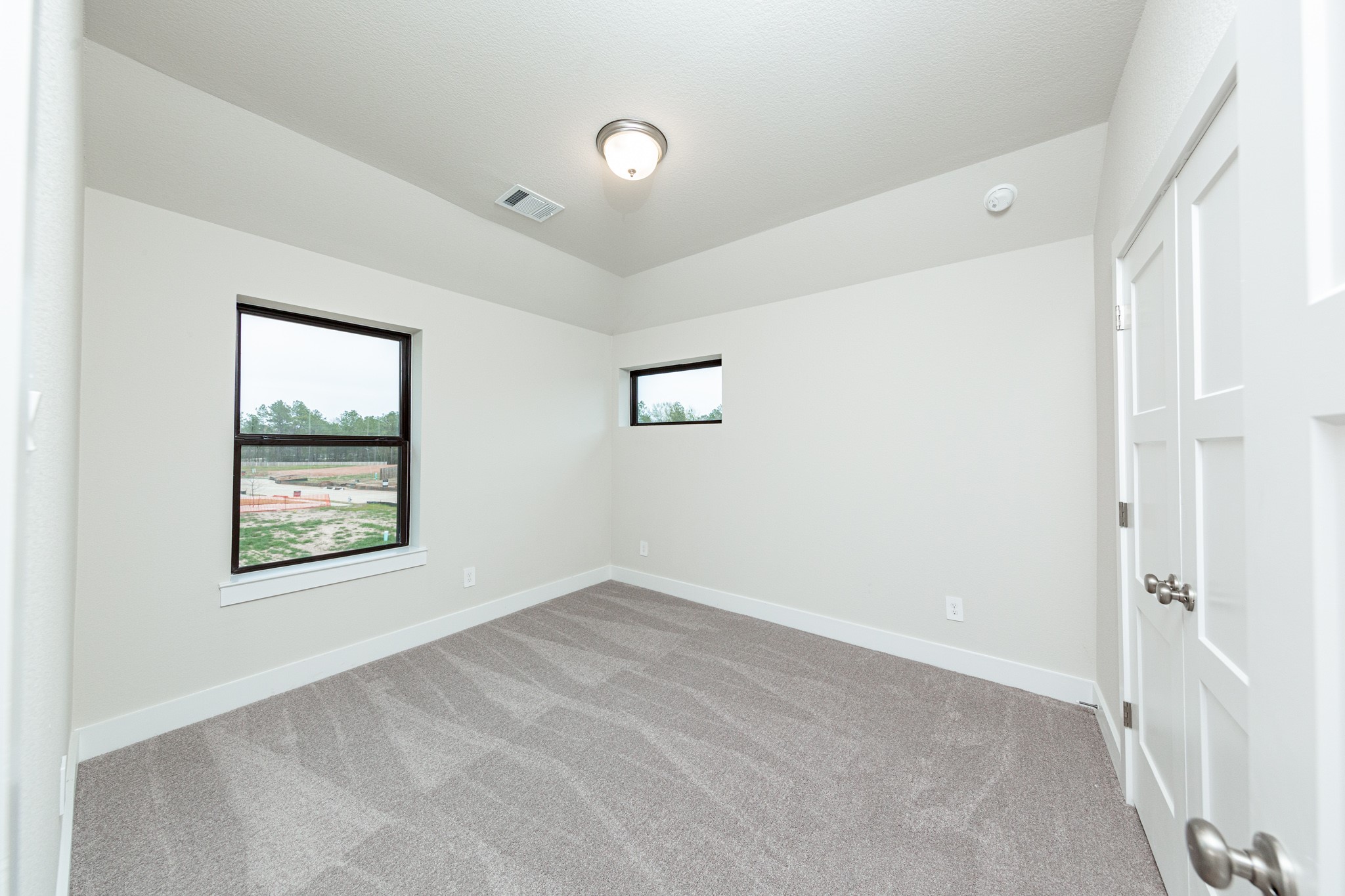 This secondary bedroom features high ceilings, plush carpet, and windows to brighten up this space with natural lighting.
