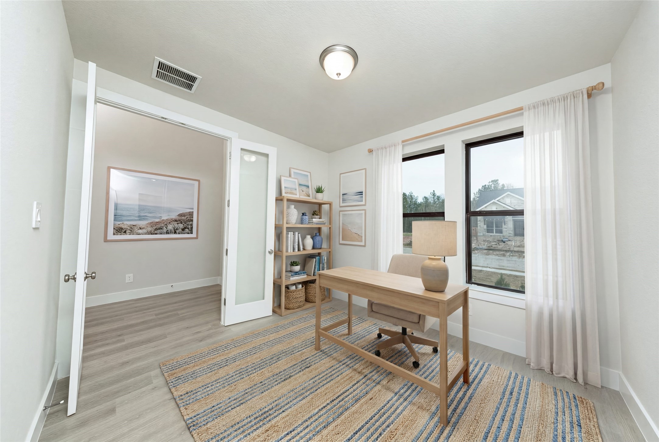 Tucked peacefully in the front of the home is this study, which features large windows, laminate flooring, French doors, and neutral toned walls. *Virtually Staged
