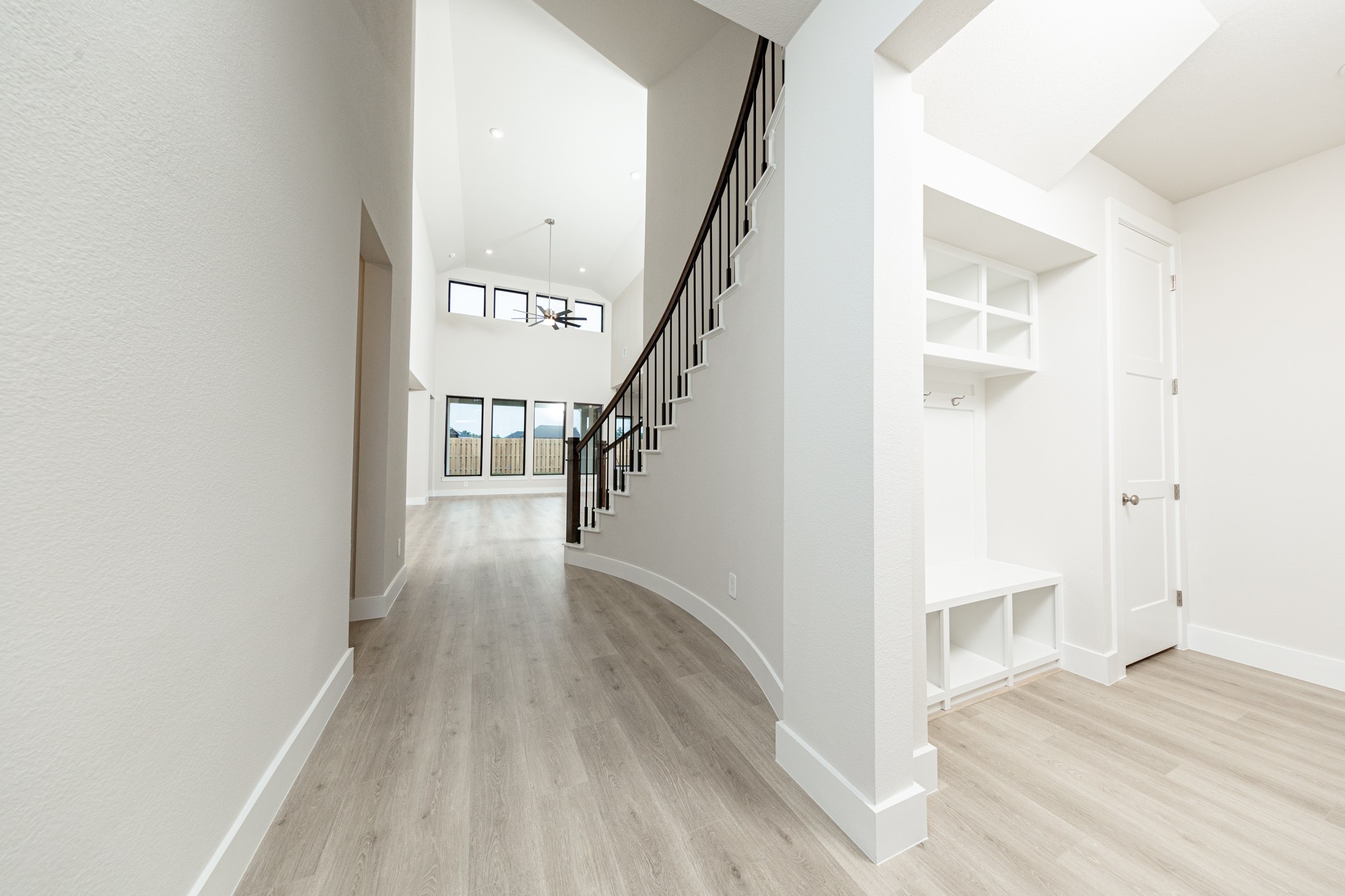 Step into this highly functional and stylish mudroom drop zone, an essential feature for a busy household. The space boasts custom-built white cabinetry and shelving, providing generous storage for coats, bags, and shoes. A comfortable built-in bench offers a convenient spot to sit, while three sleek hooks keep outerwear tidy and accessible.