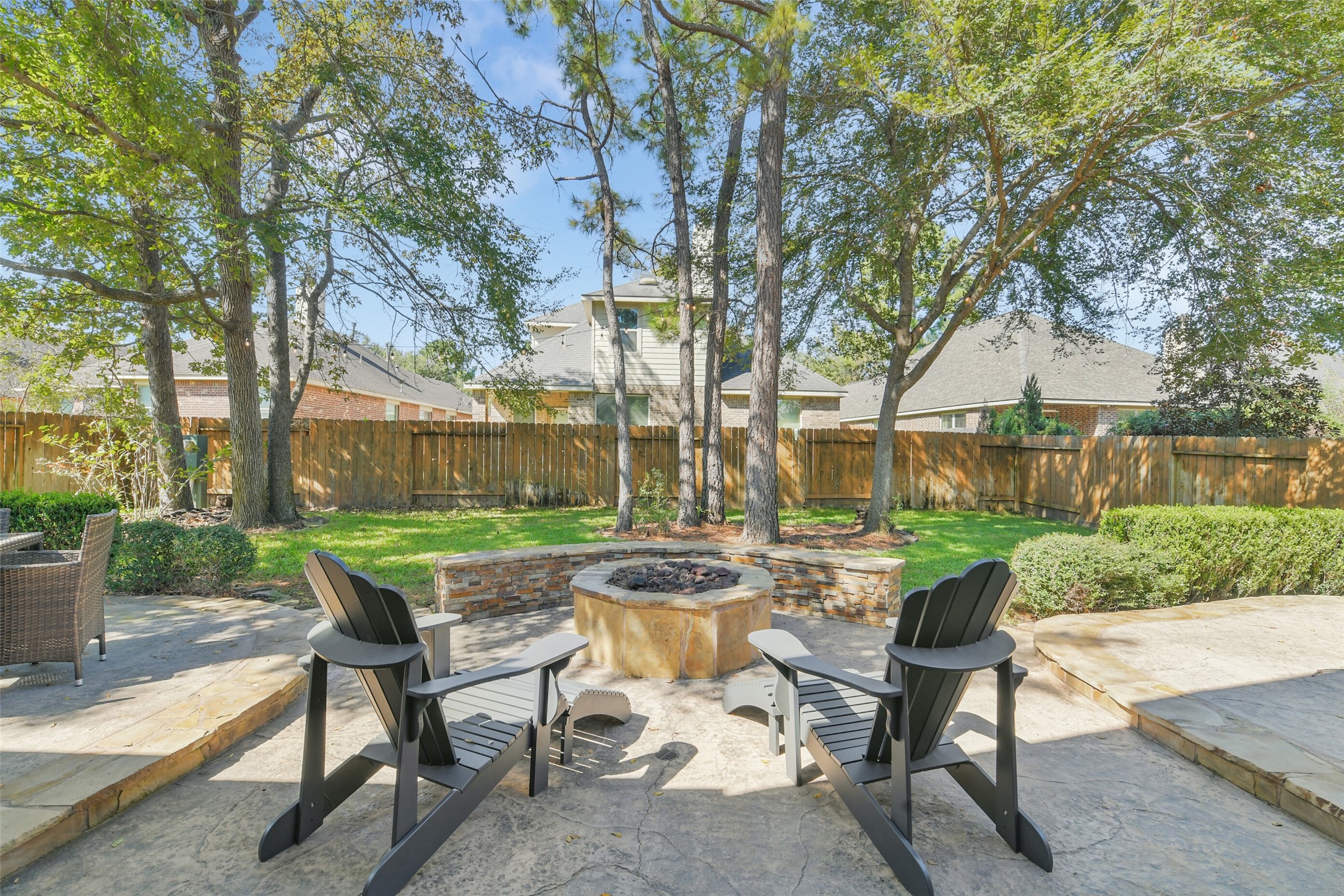 Spacious backyard patio surrounded by mature trees and attractive landscaping.