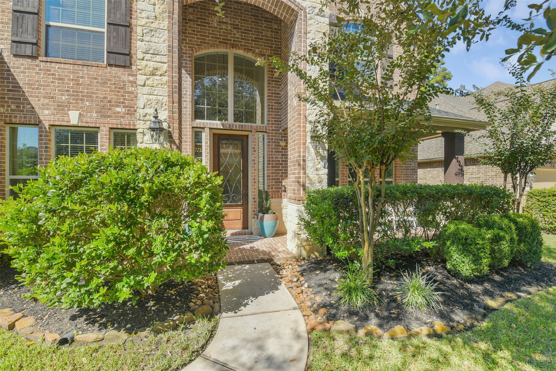 Charming front entry with attractive brickwork, mature landscaping, and a covered entrance.