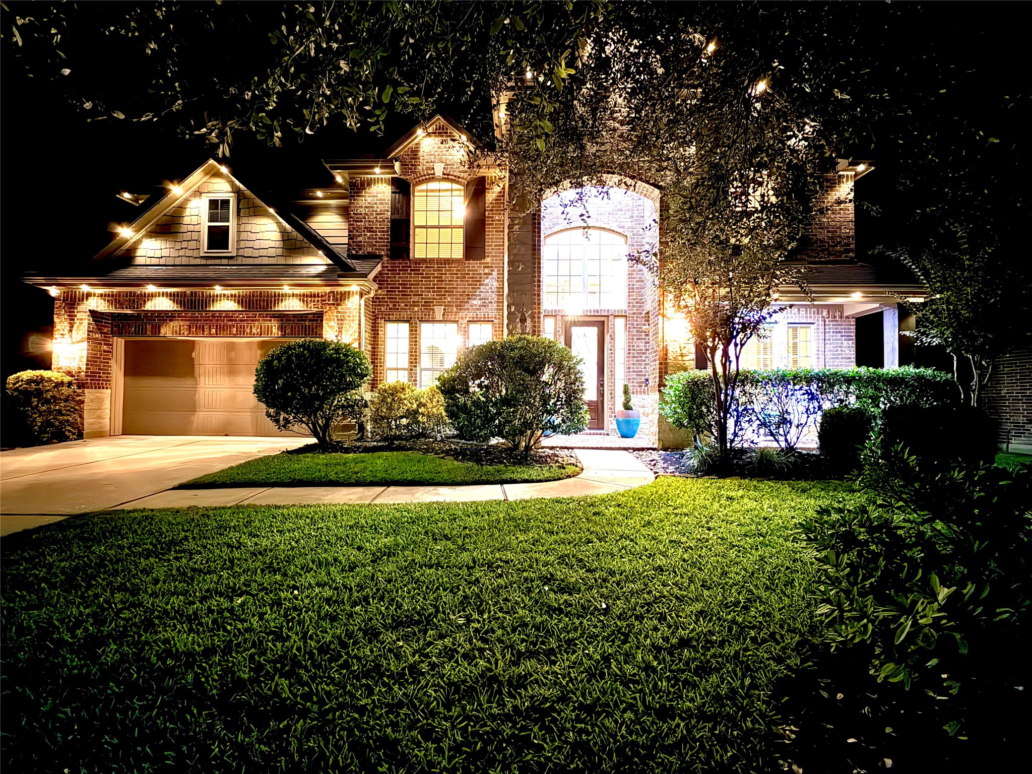 Stunning twilight view of this beautiful brick and stone home, showcasing dramatic exterior lighting