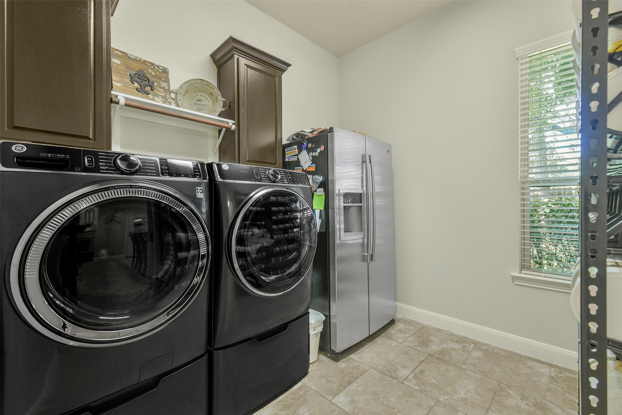 Convenient laundry room with space for full-size appliances, cabinetry, and additional storage.