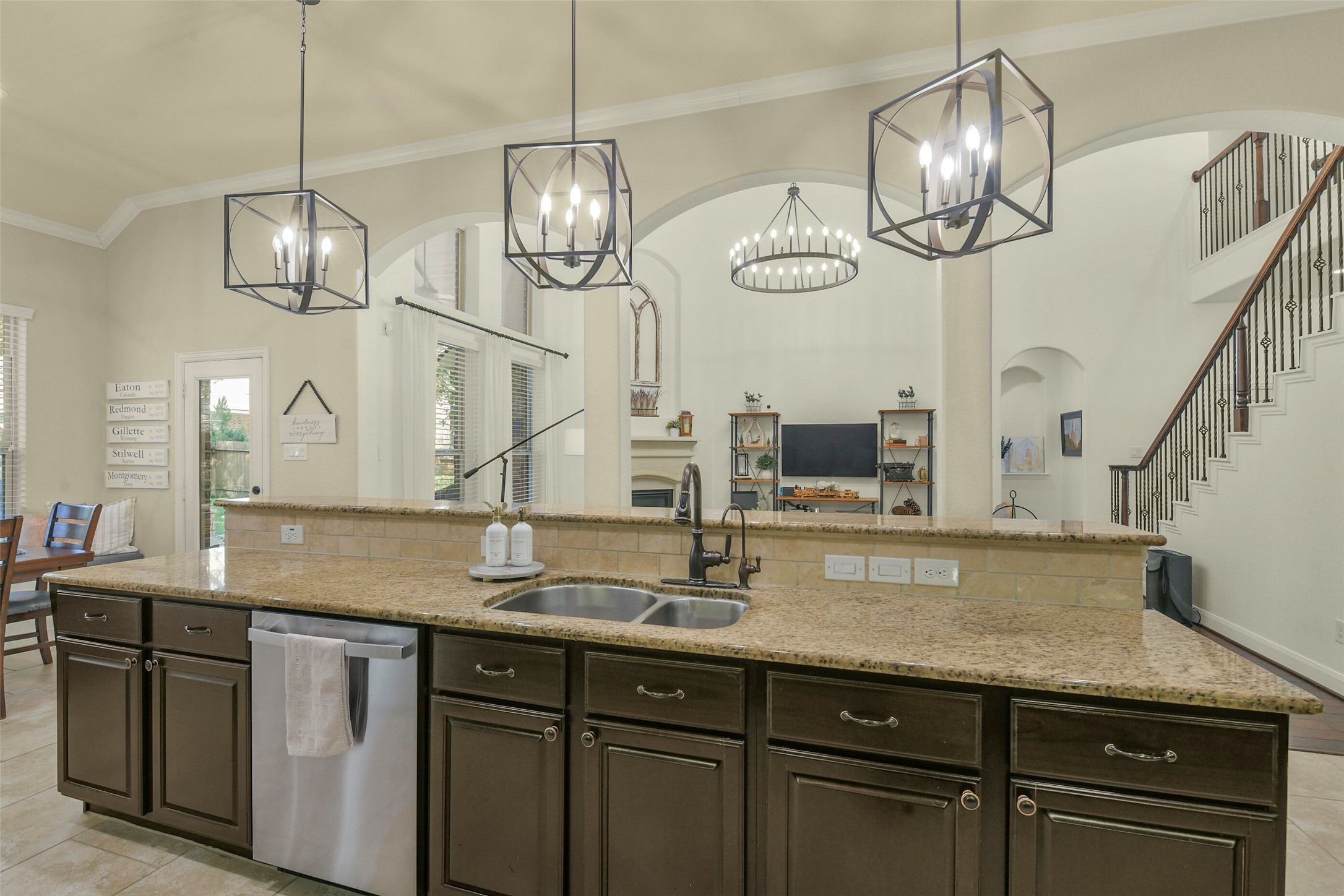 Large kitchen island with seating, pendant lighting, and an open view into the family room.