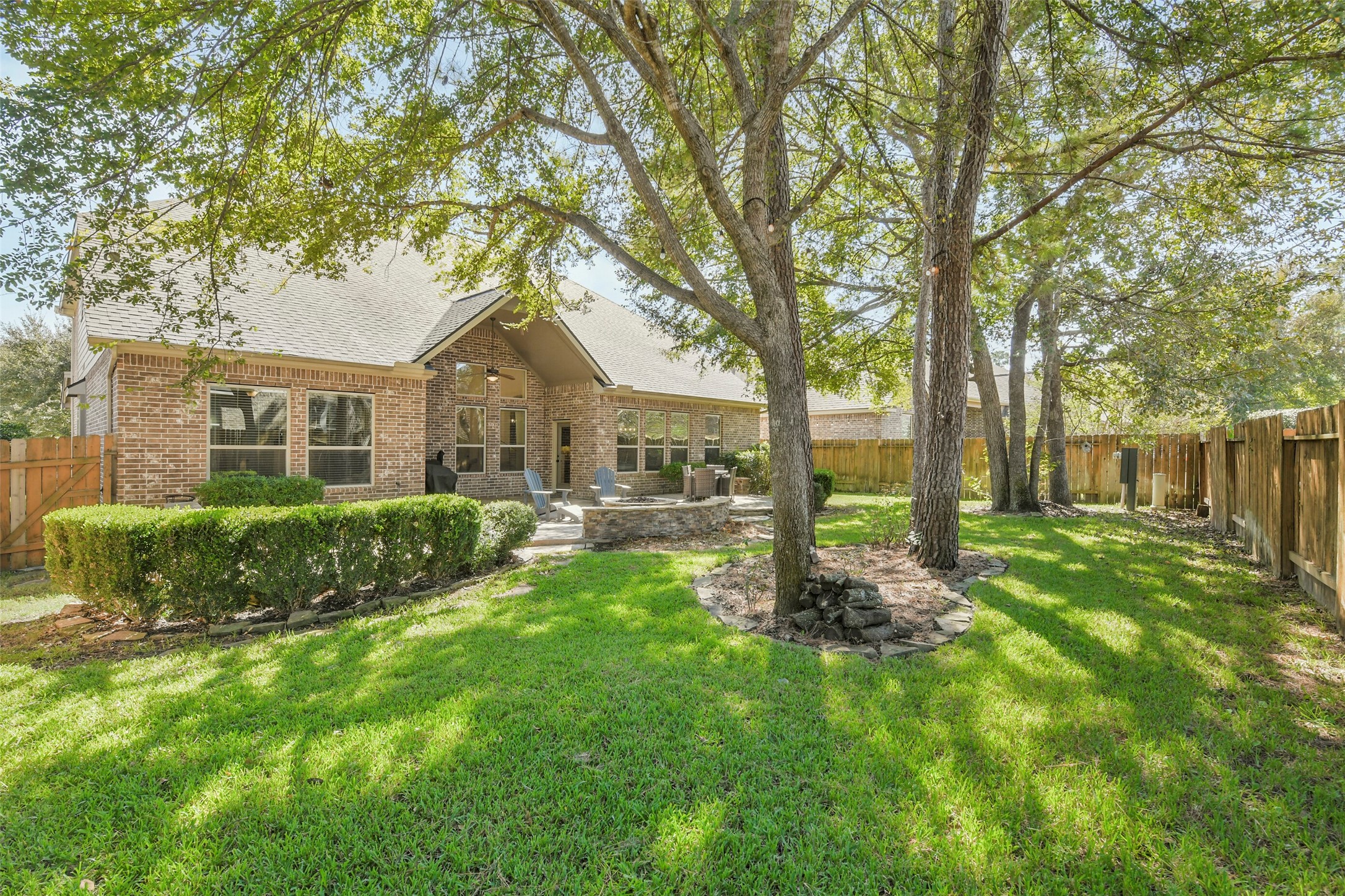Beautifully landscaped backyard with lush green lawn, mature trees, and privacy fencing.