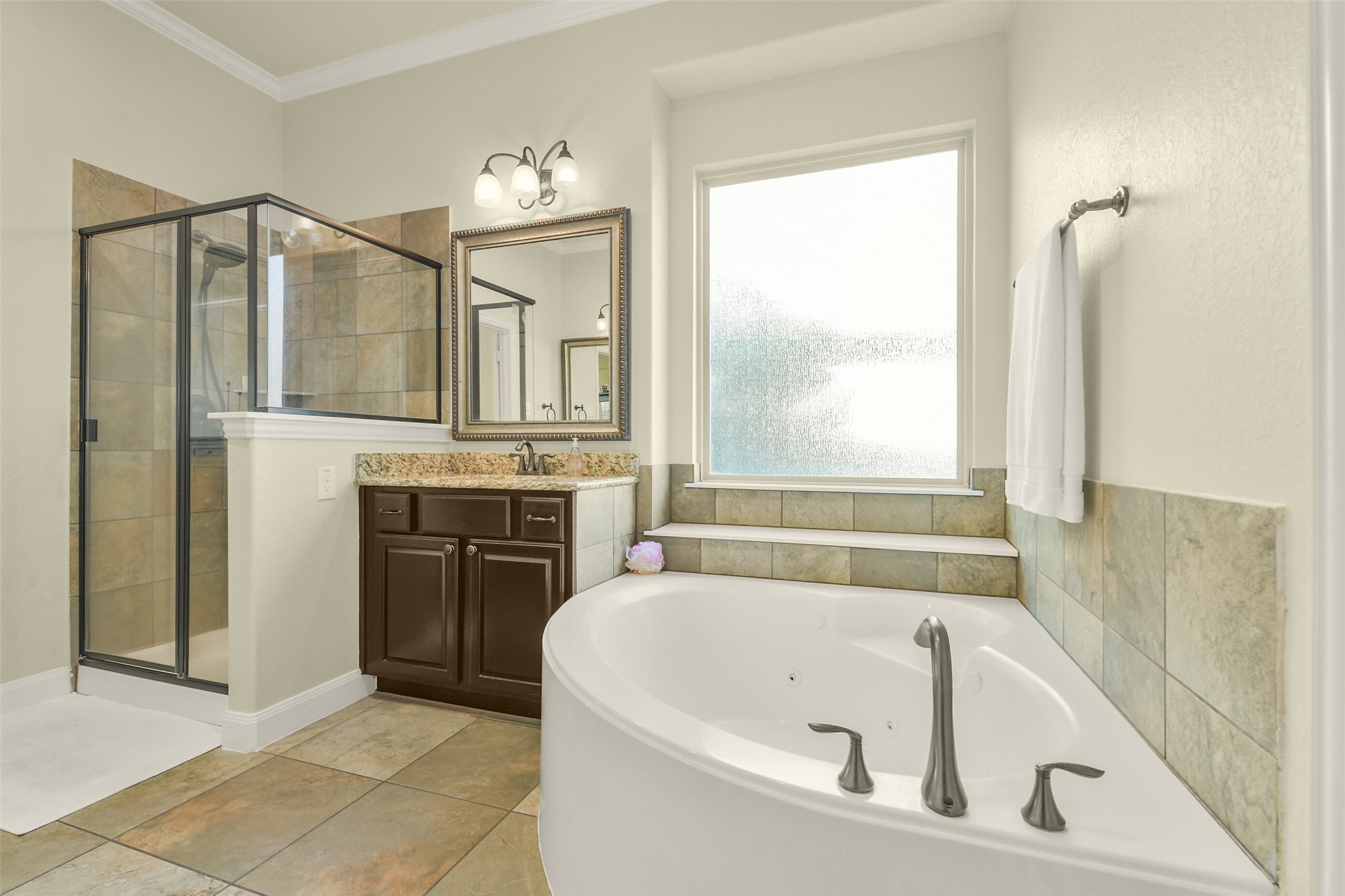 Relaxing soaking tub positioned beneath a window, with a separate shower and vanity area.