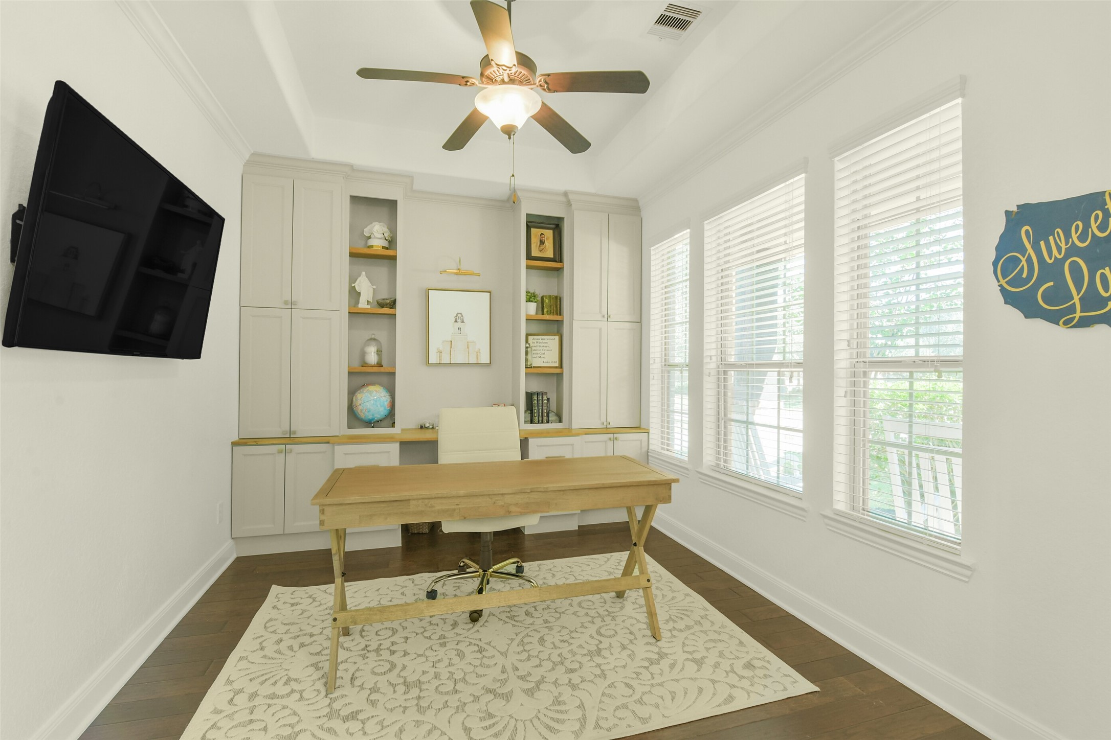 Private home office with built-in cabinetry, large windows, and ample workspace.