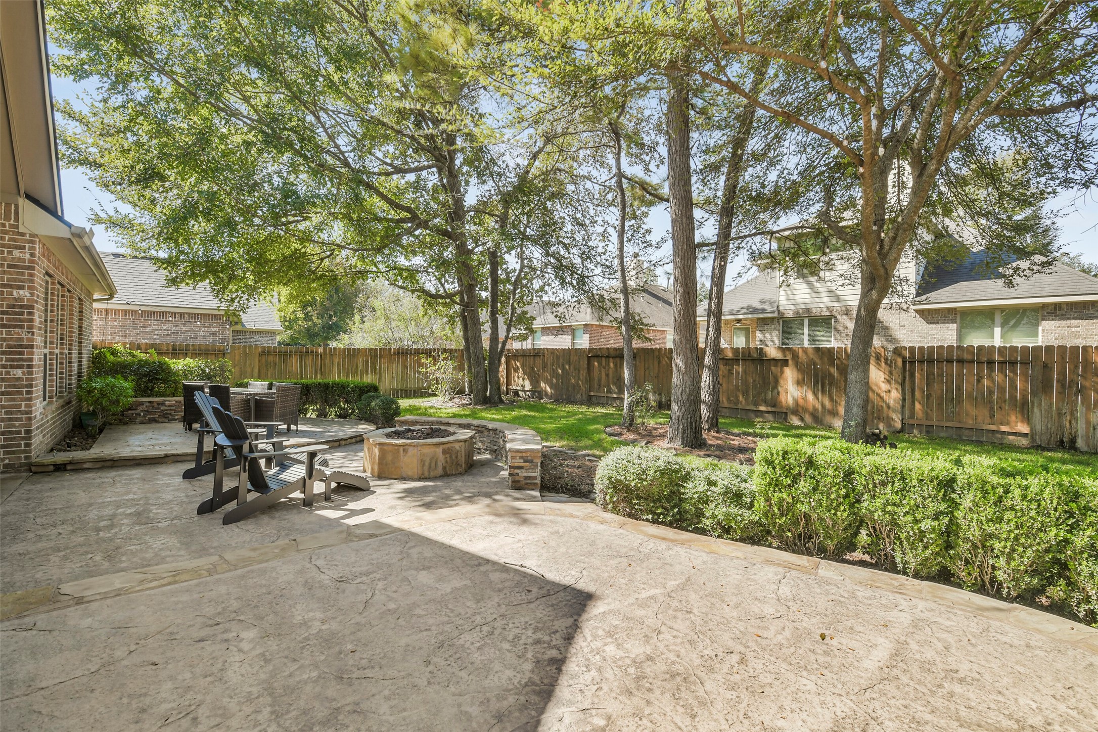 Generous backyard entertaining space with mature shade trees and multiple seating areas.