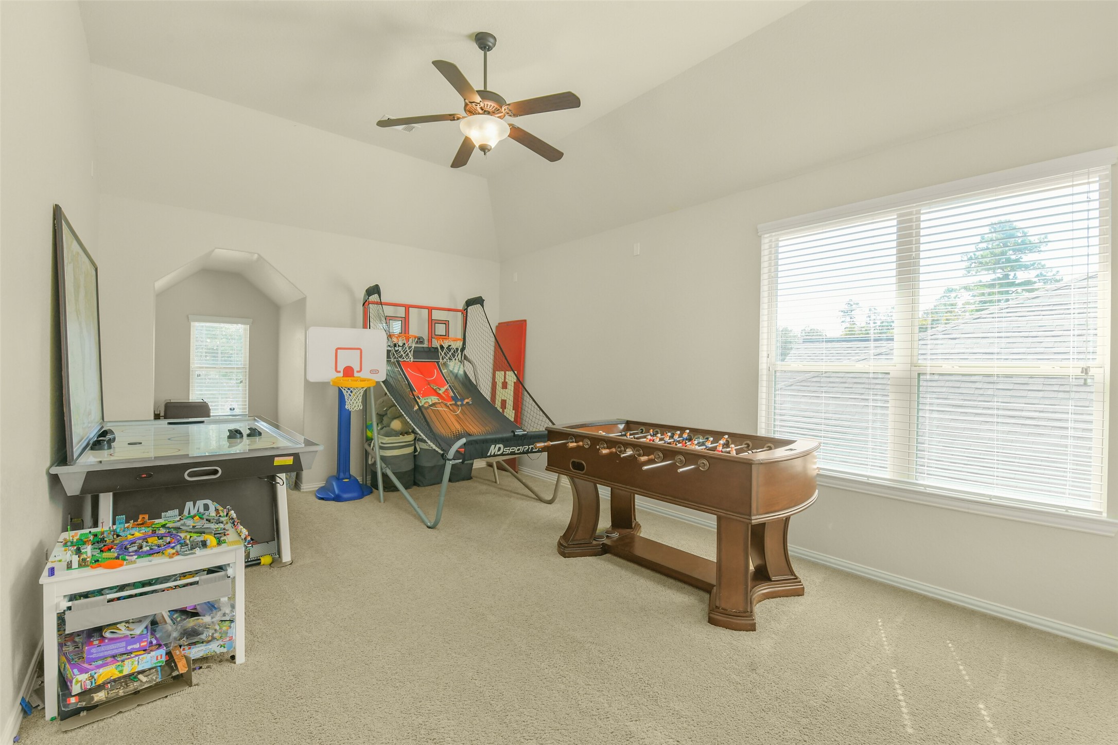 Spacious secondary bedroom featuring neutral carpeting, ceiling fan, and large windows.