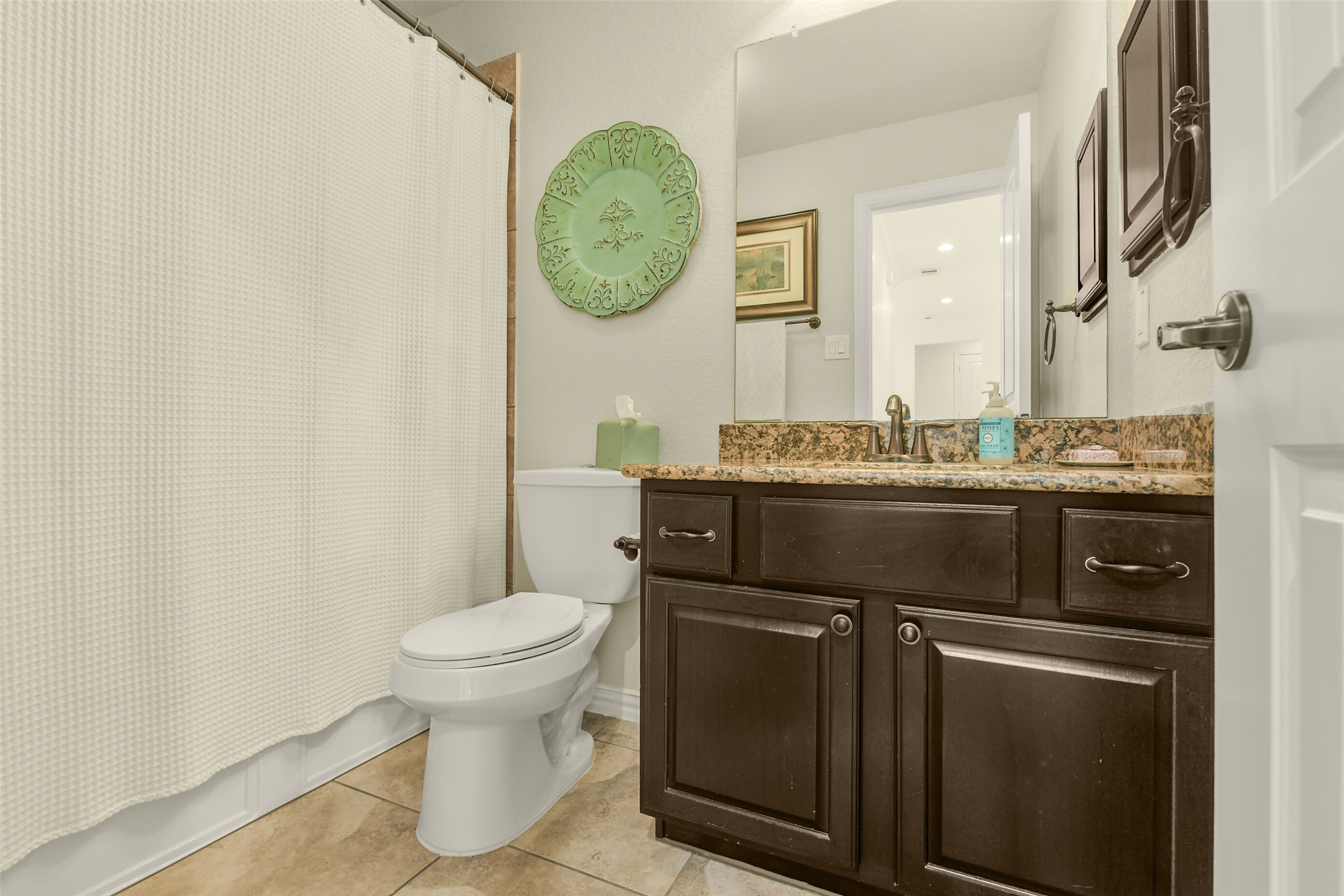 Secondary bathroom featuring a spacious vanity, framed mirror, and storage cabinetry.