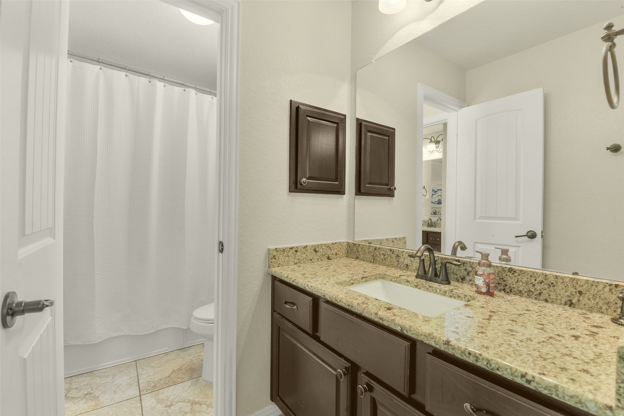 Bathroom vanity with abundant counter space, decorative lighting, and storage cabinetry.