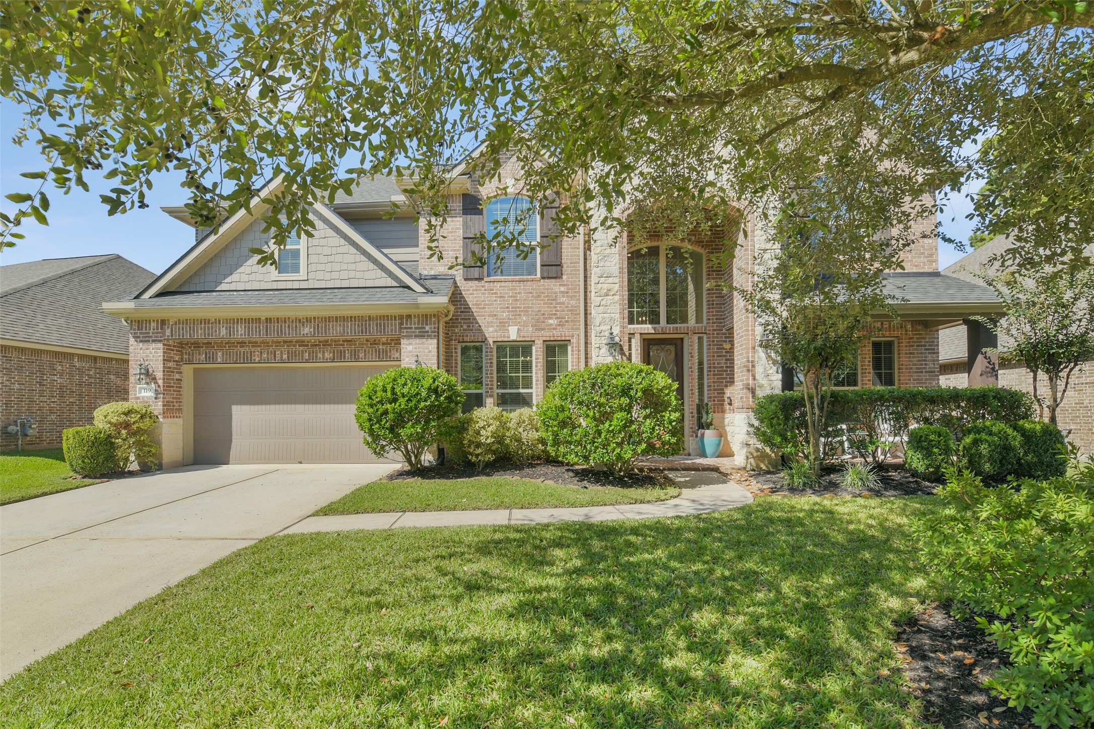 Beautiful two-story brick home with inviting curb appeal, mature trees, and a spacious driveway. Welcoming front elevation surrounded by manicured landscaping and a lush green lawn.