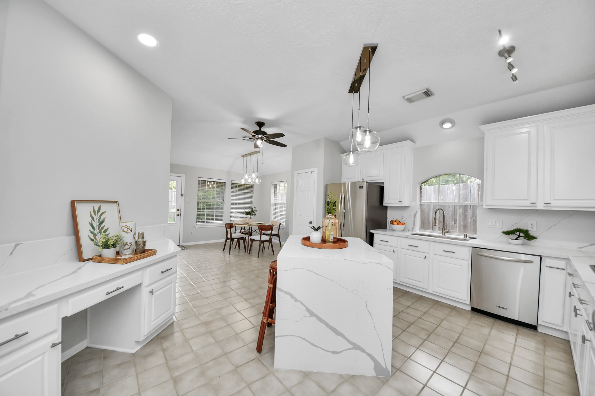 The kitchen has updated countertops and backsplash, a waterfall island with seating, and plenty of cabinets. There is also a built-in desk and a breakfast area by the windows.